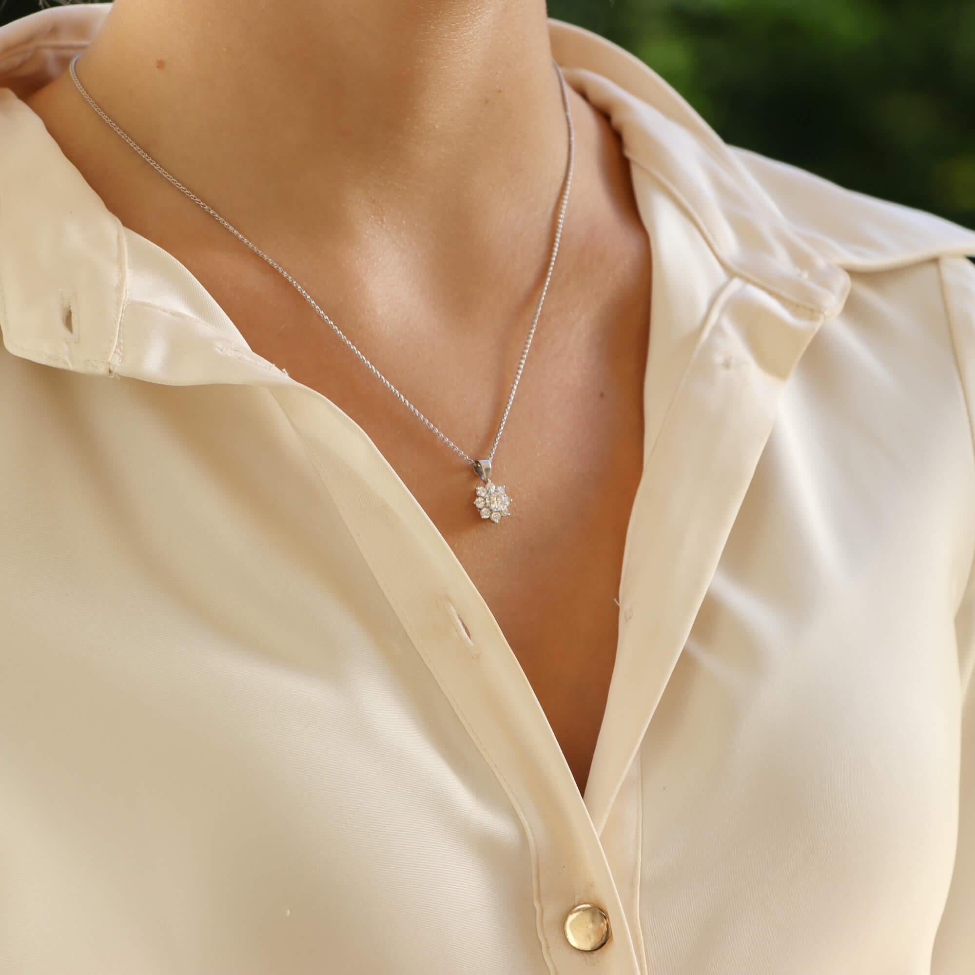 A stylish vintage floral diamond cluster pendant necklace set in 18k white gold.

The pendant is composed of nine round brilliant cut diamonds which are securely set in a daisy floral motif. The pendant hangs from a solid white gold bail and is