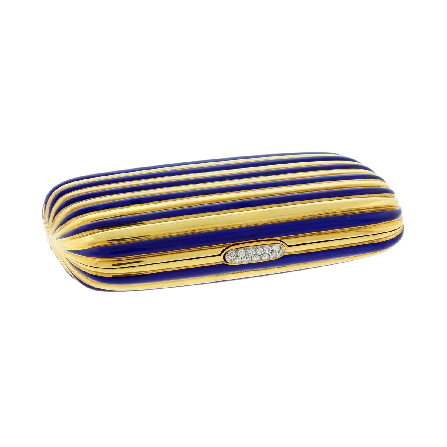 A lovely mirrored powder compact featuring a striped design in 18K yellow gold and vibrant blue enamel. The compact opens with a press on the diamond clasp.  Opening the case reveals a mirror and open powder compartment.

Case Length: 3 inches
Case