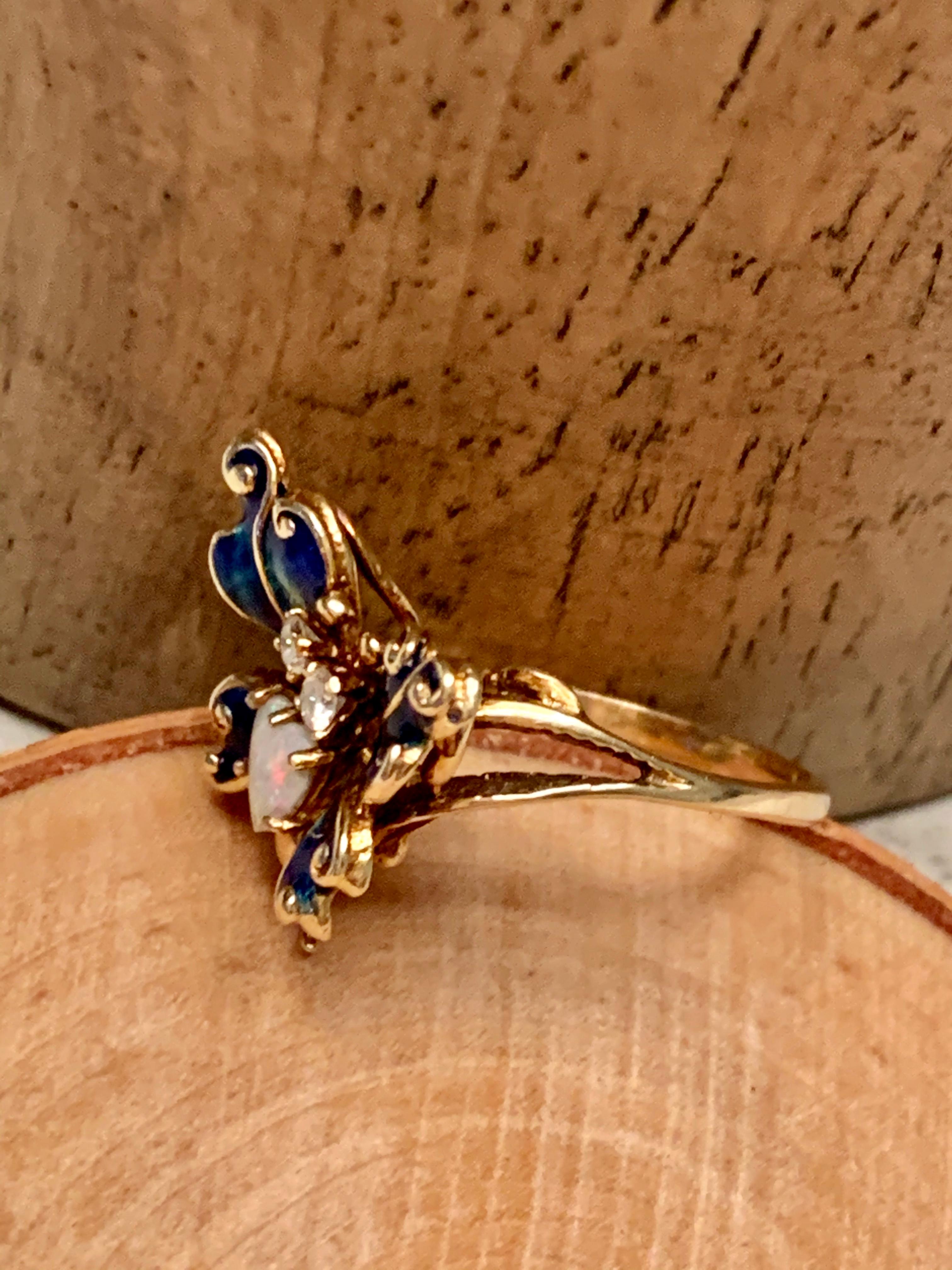 This gorgeous butterfly looks as if it just landed on your finger!  It features one 5.5mm heart shaped Opal and 2-2.5mm Diamonds which are .12ctw.  Grade: Si(2)-G
The butterfly is 14 karat yellow Gold and features beautiful blue enamel work to