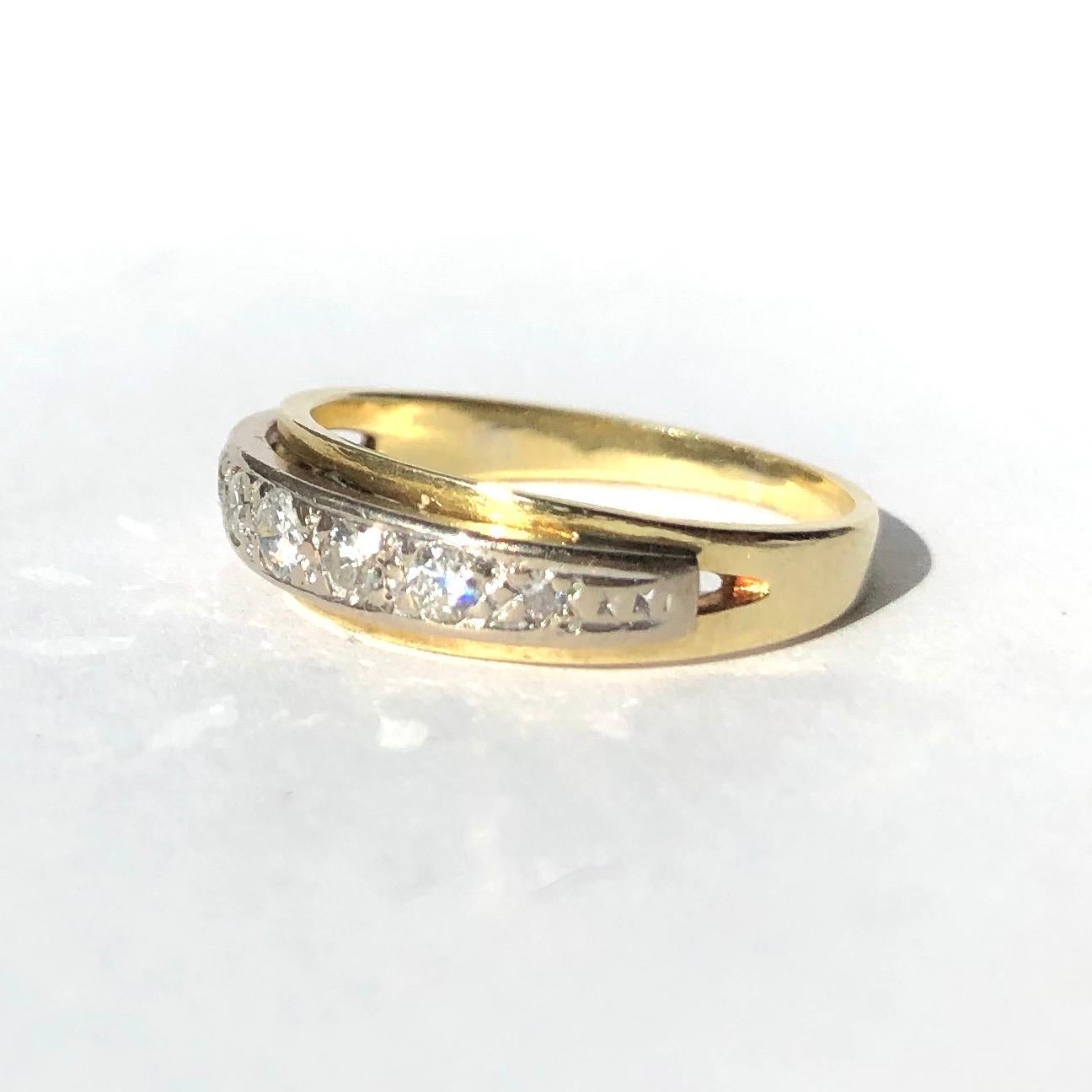 Sitting round upon this 18ct yellow gold band is a platinum panel which holds seven diamonds. The stones graduate in size with the largest diamond at the centre measures 10pts and the smallest measures 3pts. Made in London, England. 

Ring Size: L