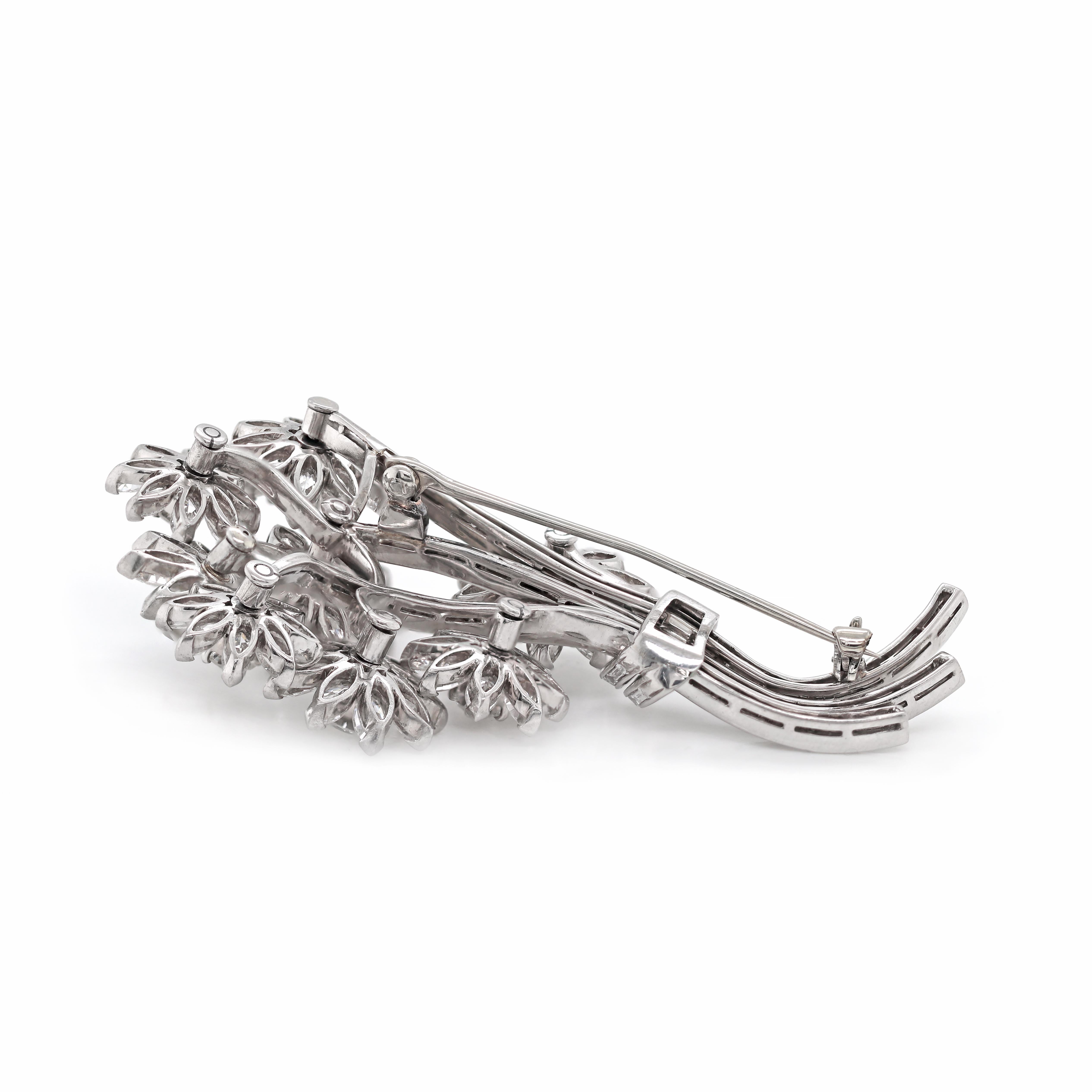 This incredible flower bouquet brooch features 8 rotating flowers, claw set with a round brilliant cut diamond in the center of 8-10 marquise shaped diamond petals. The flowers are beautifully connected to a spray of three baguette cut diamond set