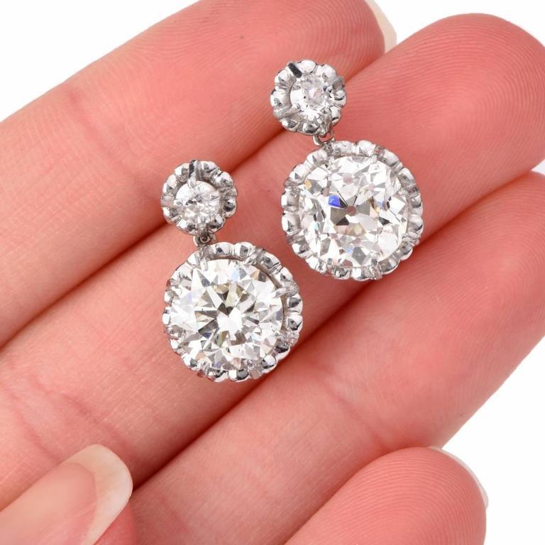 These captivating vintage earrings are crafted in platinum, weigh cumulatively 6.8 grams and each measure 18 mm long. The two large diamonds weigh cumulatively 6.05 carats in total and are graded I-J color and VS2 to SI1 clarity. And two smaller