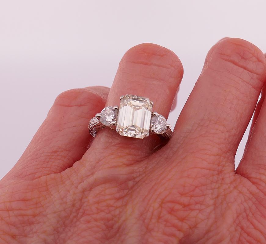 A gorgeous vintage three-stone diamond ring, made in platinum.
This three-stone ring features an emerald cut diamond flanked by two round brilliant cut diamonds. The center diamond is four-prong set, and the side diamonds are three-prong set. 
The