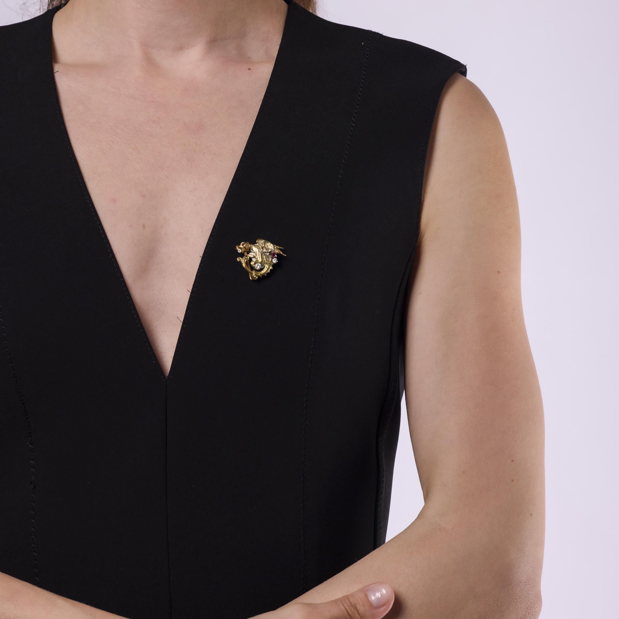 Cette broche vintage Brilliante des années 1960 est réalisée en or jaune 10k et présente trois diamants ronds de taille brillant totalisant environ 0,20 carats, de couleur G-H et de pureté SI. Deux rubis de taille ronde, pesant environ 0,15 carat,