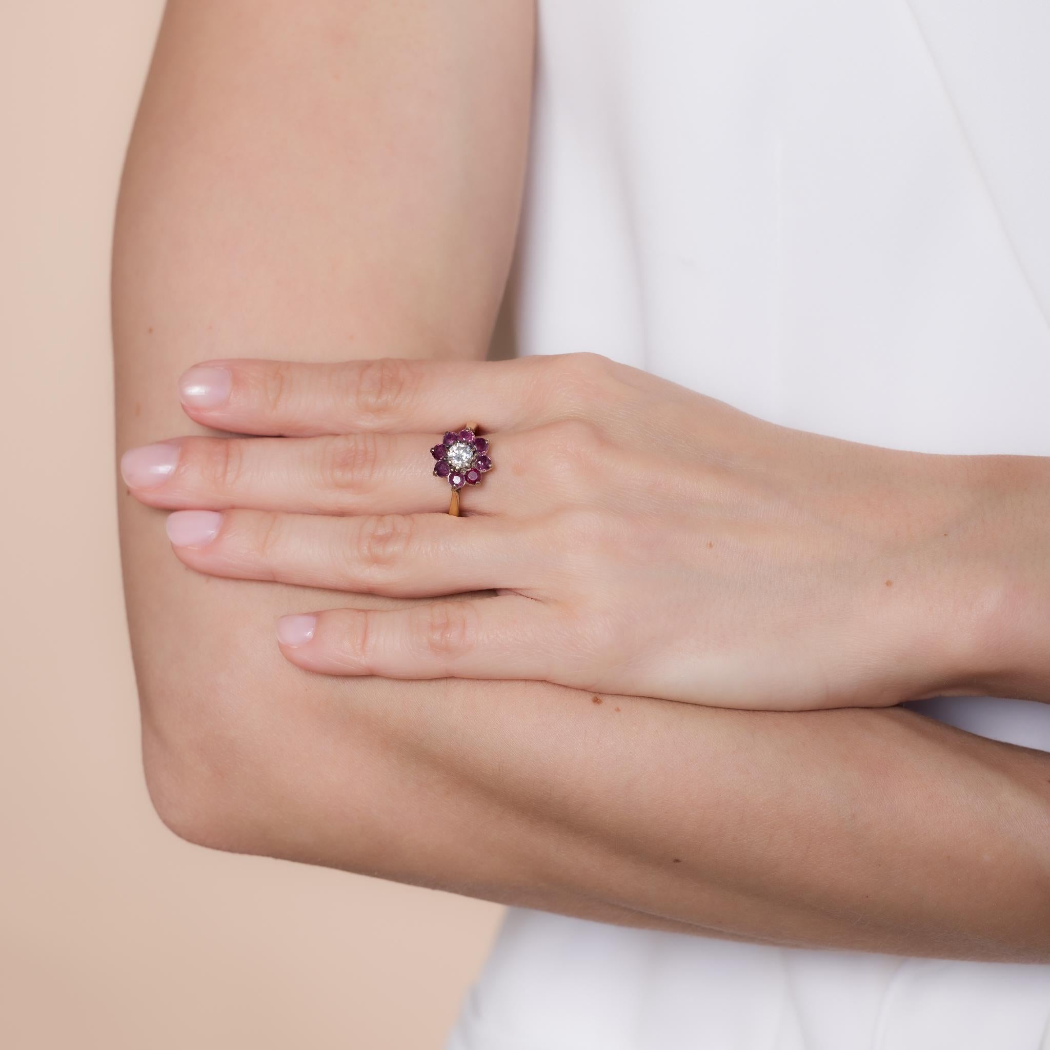 Crafted in the 1980s, this vintage flower ring is designed in 18k yellow gold and showcases a round brilliant cut diamond weighing approximately .50 carats, graded F color and I clarity. Surrounding the center stone are 8 round brilliant cut rubies