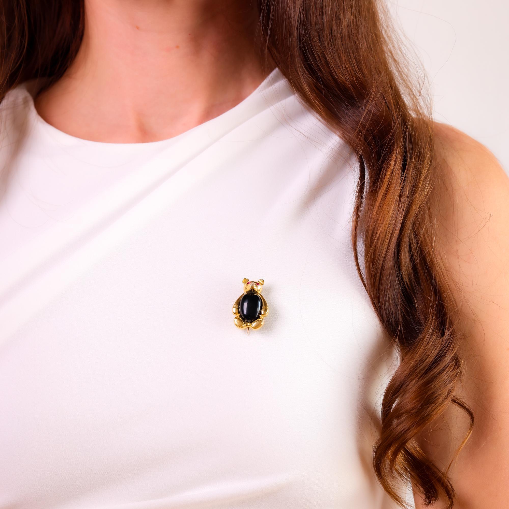 This charming vintage 1970s 18k yellow gold Teddy Bear brooch features a sparkling diamond, vibrant rubies, and onyx accents, blending playful design with luxury.

Center stone: Old mine cut diamond
Weight: Approximately .0.04 carat
Color: