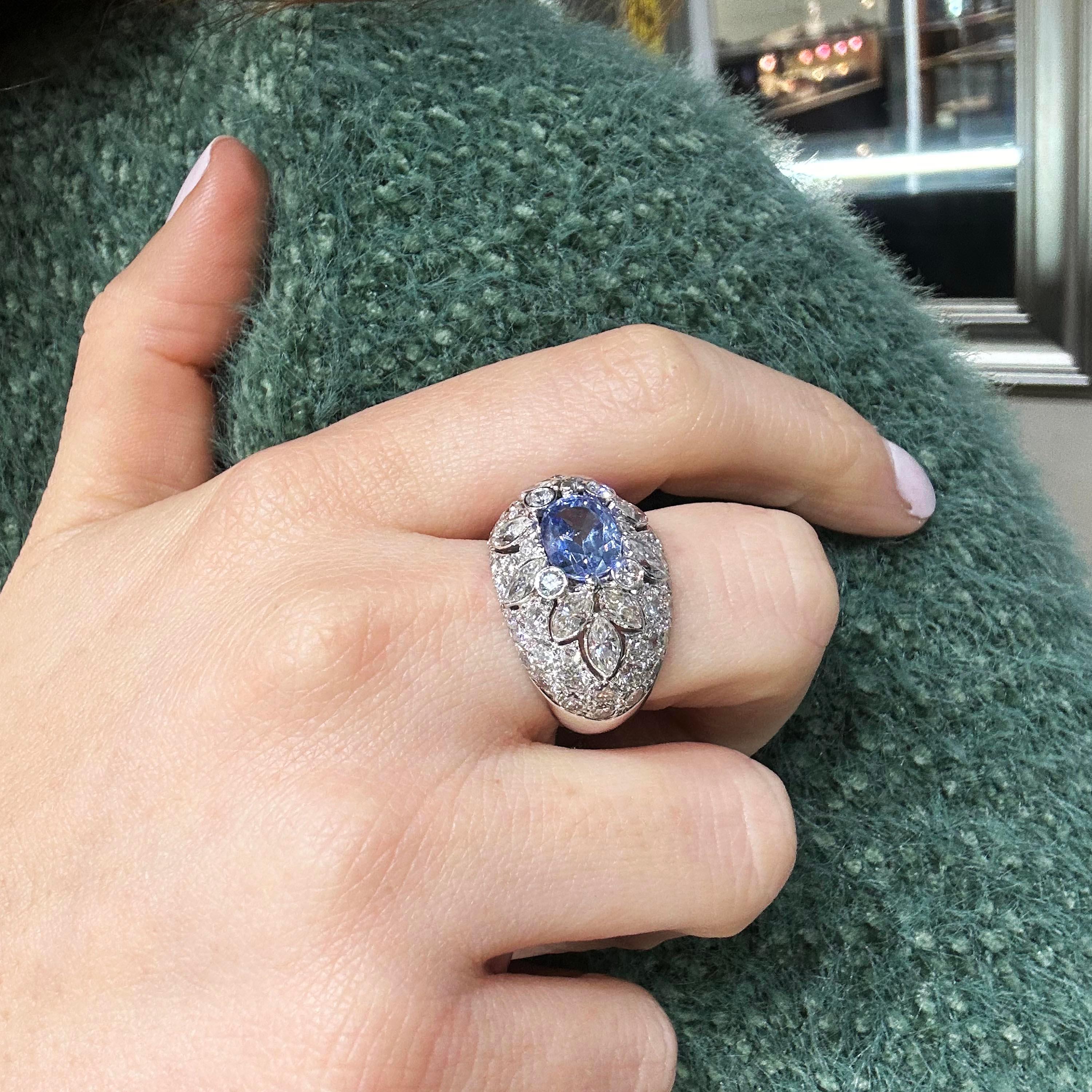 A vintage sapphire, diamond and platinum bombé ring, set with an oval faceted Ceylon sapphire, with a surround of four round brilliant-cut diamonds and ten marquise sapphires in rub over settings and a surrounding bombé dome of pavé set round