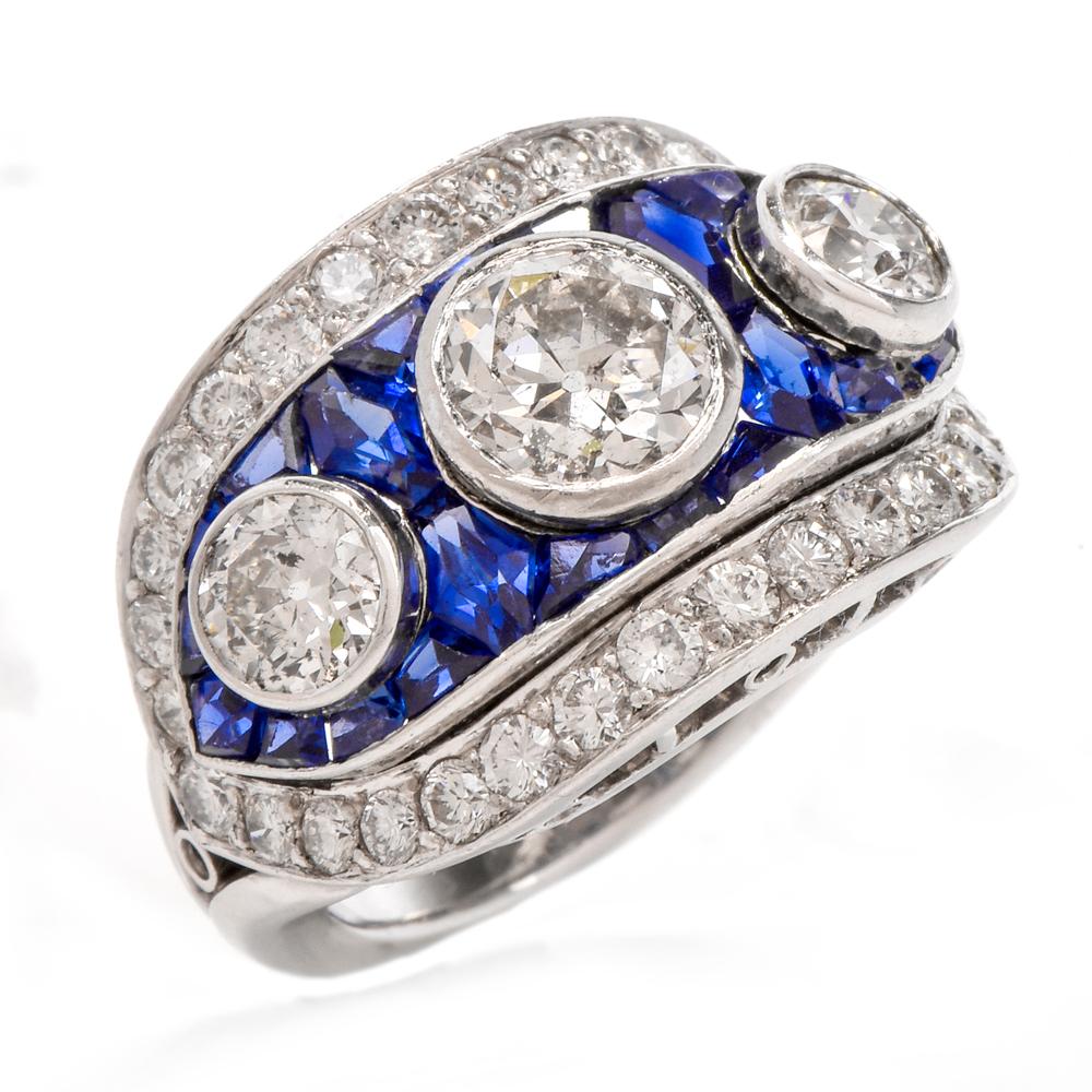  This lovely Art Deco with diamonds and sapphires is crafted in platinum, weighing 10.1 grams and measuring 14 mm wide. Designed as a gracefully convex hexagonal plaque, the ring is adorned with three large European-cut diamonds, cumulatively