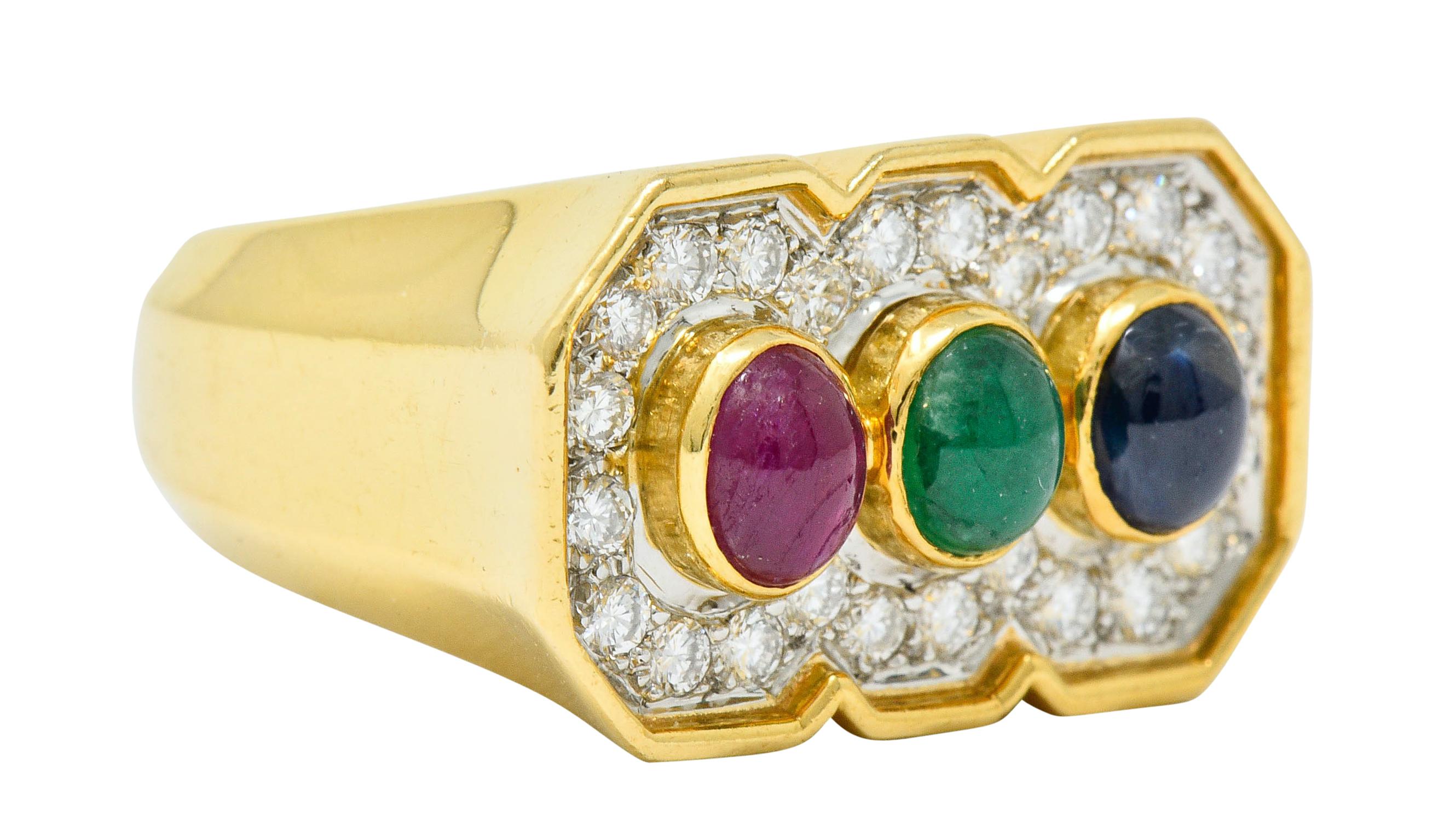 Rectangular mounting centers three bezel set cabochons of ruby, sapphire, and emerald

Translucent and brightly colored while weighing in total approximately 1.50 carats

Surrounded by a recessed geometric halo of round brilliant cut diamonds, bead