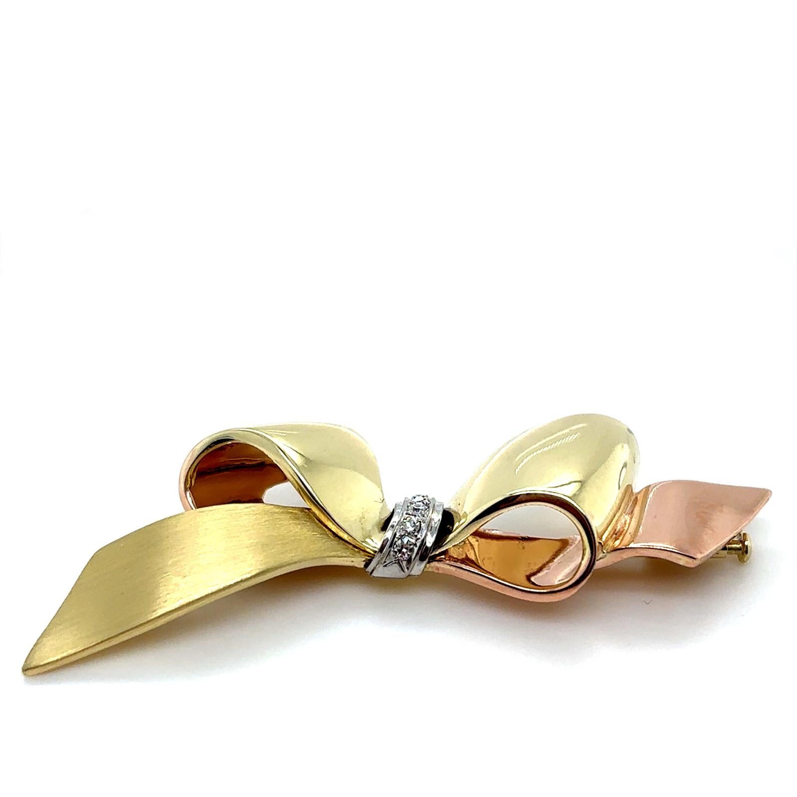 A vintage diamond set bow brooch in 14 karat yellow, white and rose gold, circa 1960

This statement brooch is designed as a stylized bow, in plain polished and satin finish yellow and rose gold.
Diamonds are grain set to the centre knot in