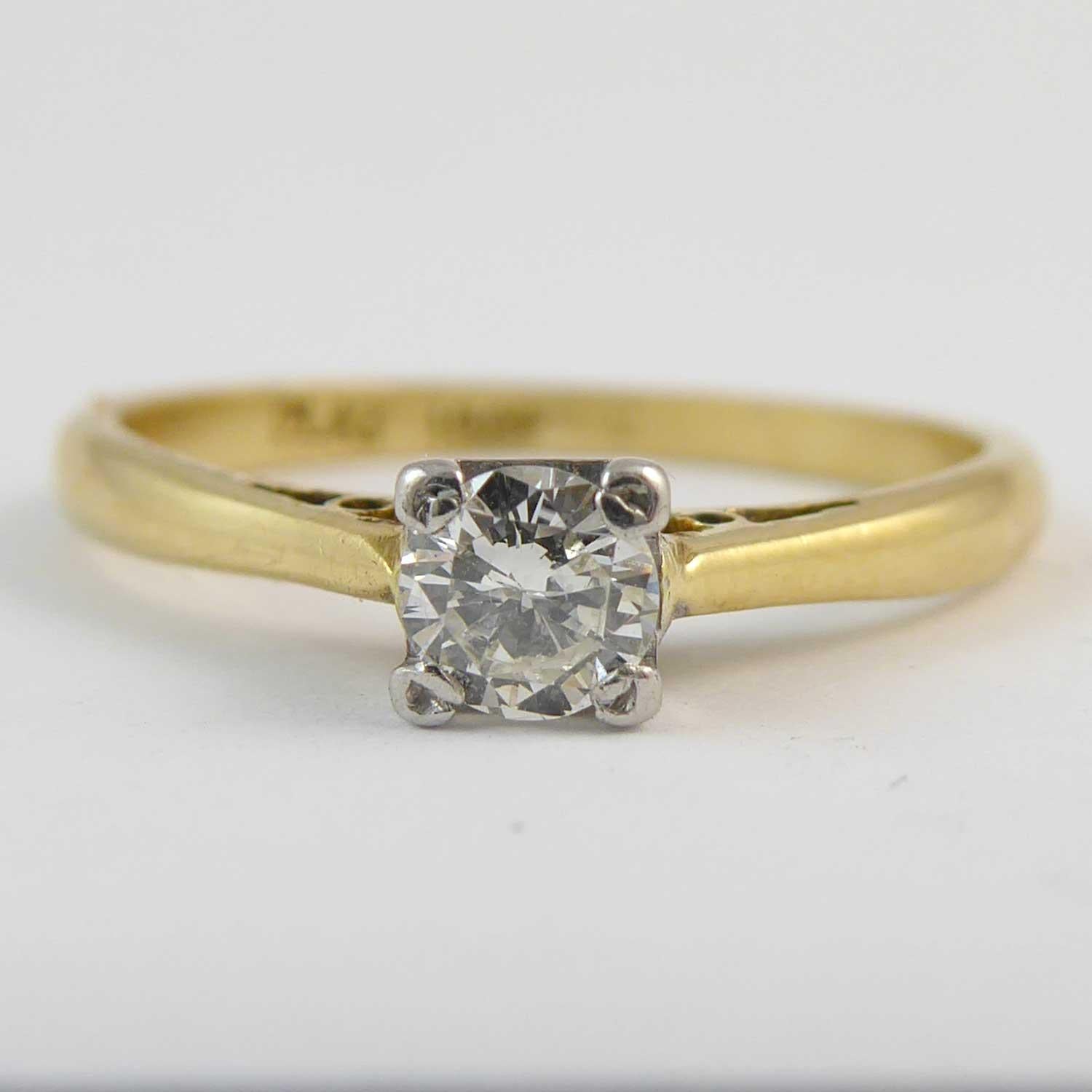 A dainty solitaire diamond ring just perfect for the petite hand.  Comprising a round brilliant cut diamond measuring approx. 4.0mm diameter set in four white rub-over claws creating a square appearance to a white square mount.  Yellow D shaped