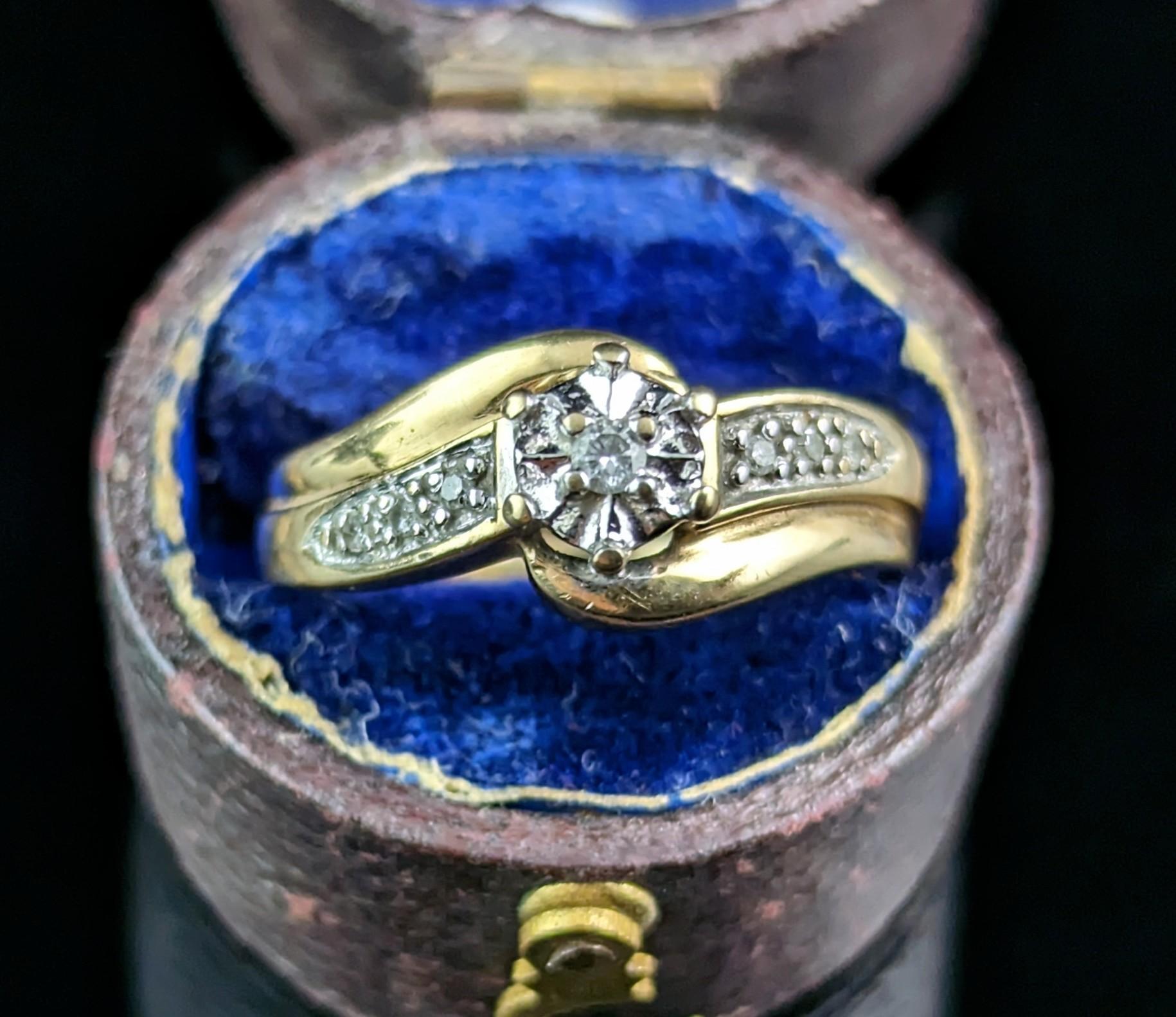 A pretty vintage Diamond Crossover ring in 9ct yellow gold.

A chunky 9ct gold band with a cross over design face and shoulders, the shoulders are set with diamond chips and the front houses a single diamond in a 9ct white gold illusion setting.

It