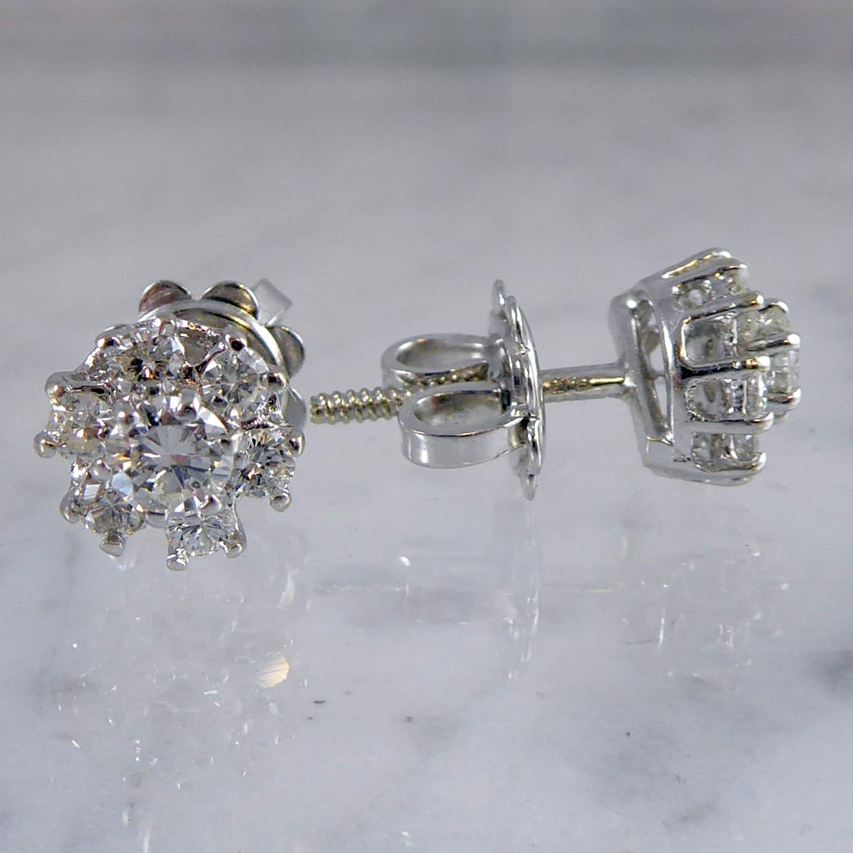 A very pretty pair of vintage diamond earrings featuring seven brilliant cut diamonds to each ear stud in white claw settings to a basket style mount.  White gold posts with screw thread fittings and white butterflies for pierced ears only. 