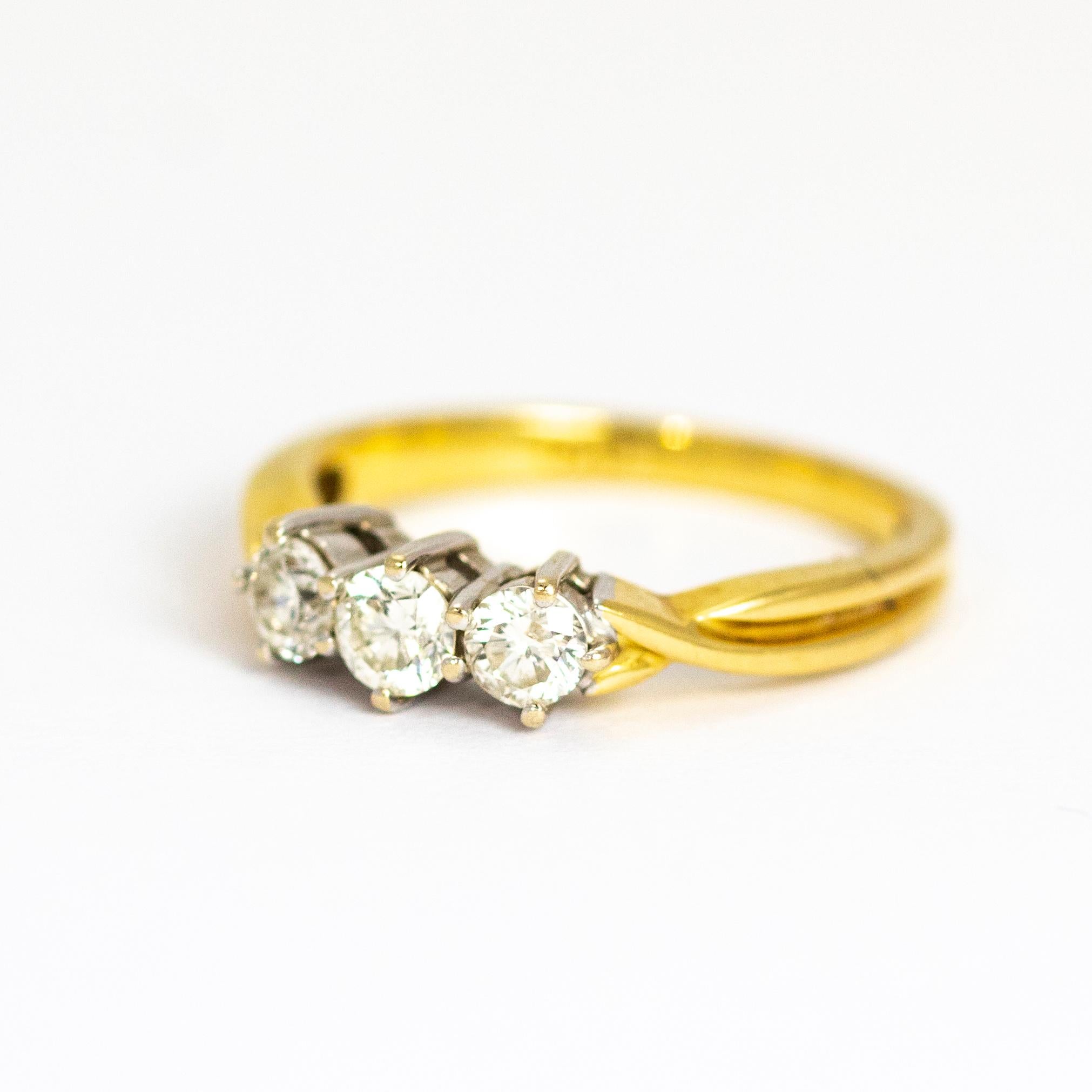 This vintage 18 Carat Gold and platinum beauty holds three bright diamonds with a total weight of 50pts and features twisted gold shoulders. Made in London, England. 

Ring Size: M or 6 1/4