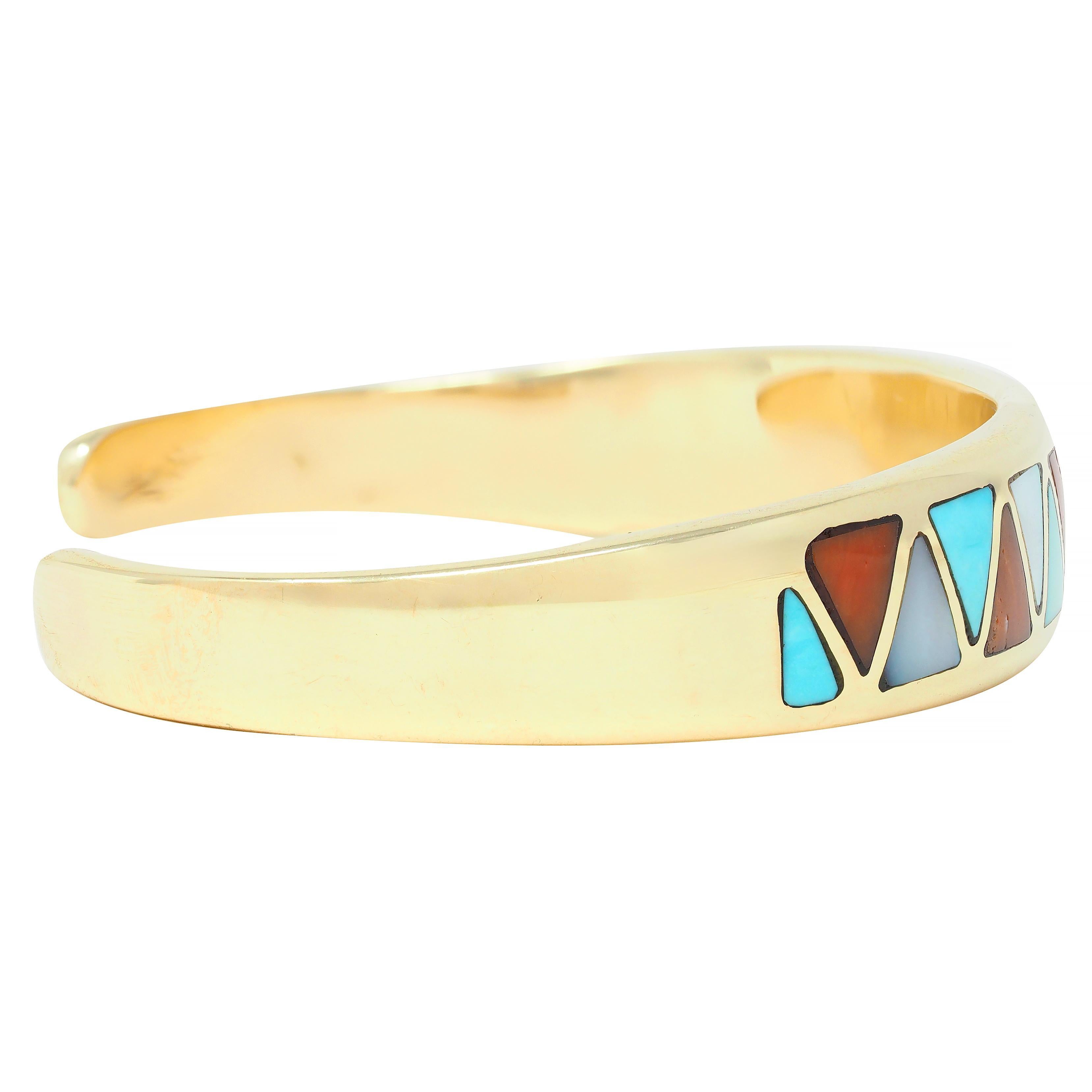 Designed as an open cuff form featuring a zig-zag motif inlay 
Comprised of turquoise, carnelian, and mother-of-pearl 
Opaque robin's egg blue, reddish-orange, and iridescent white
Carved triangular forms alternating in pattern 
Accented by a round