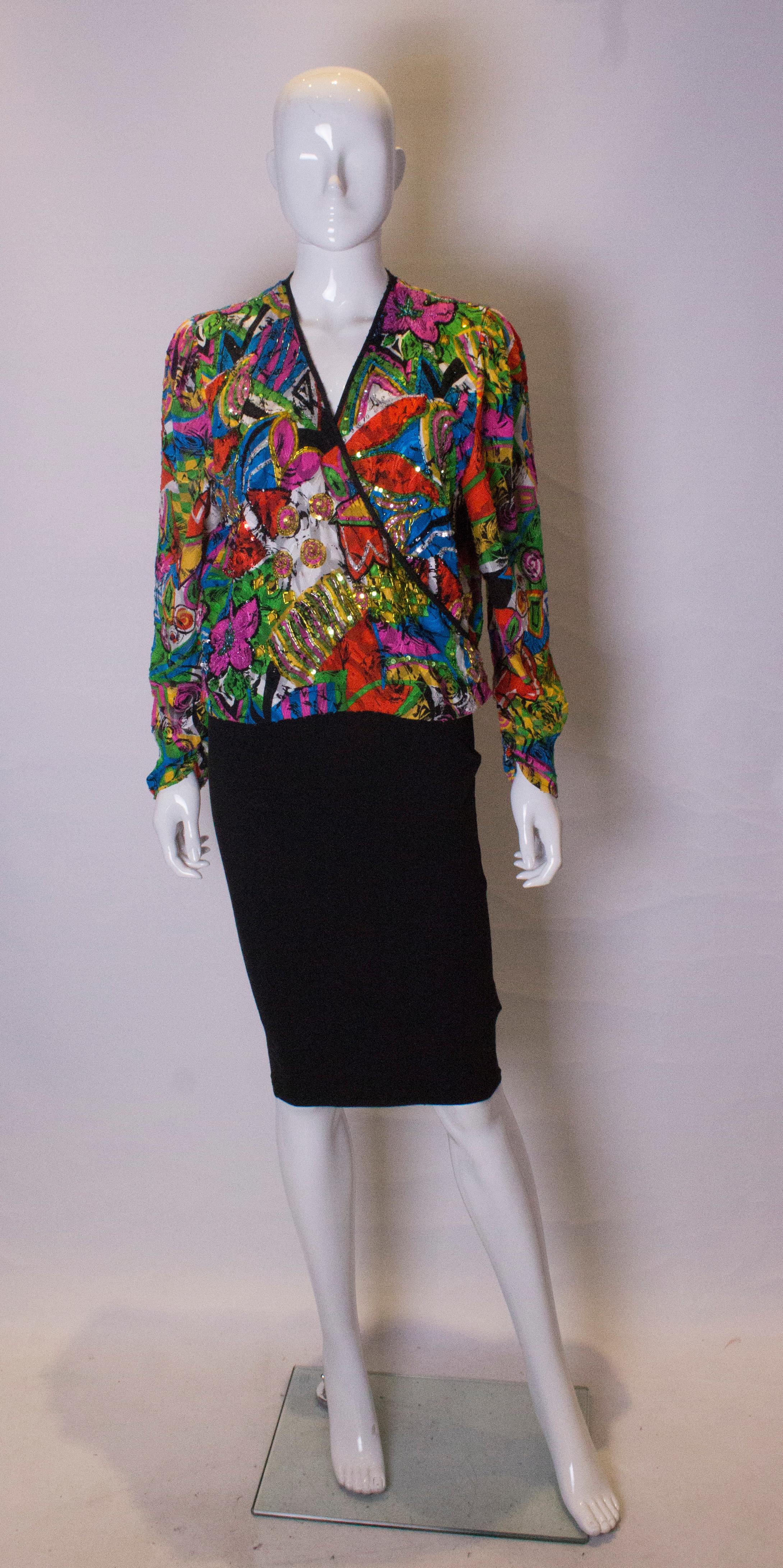 A fun top by Diane Fres. The top has a wrap over front with bead and sequin detail. It as gathering at the cuffs , elastic at the base and is edged in black.
