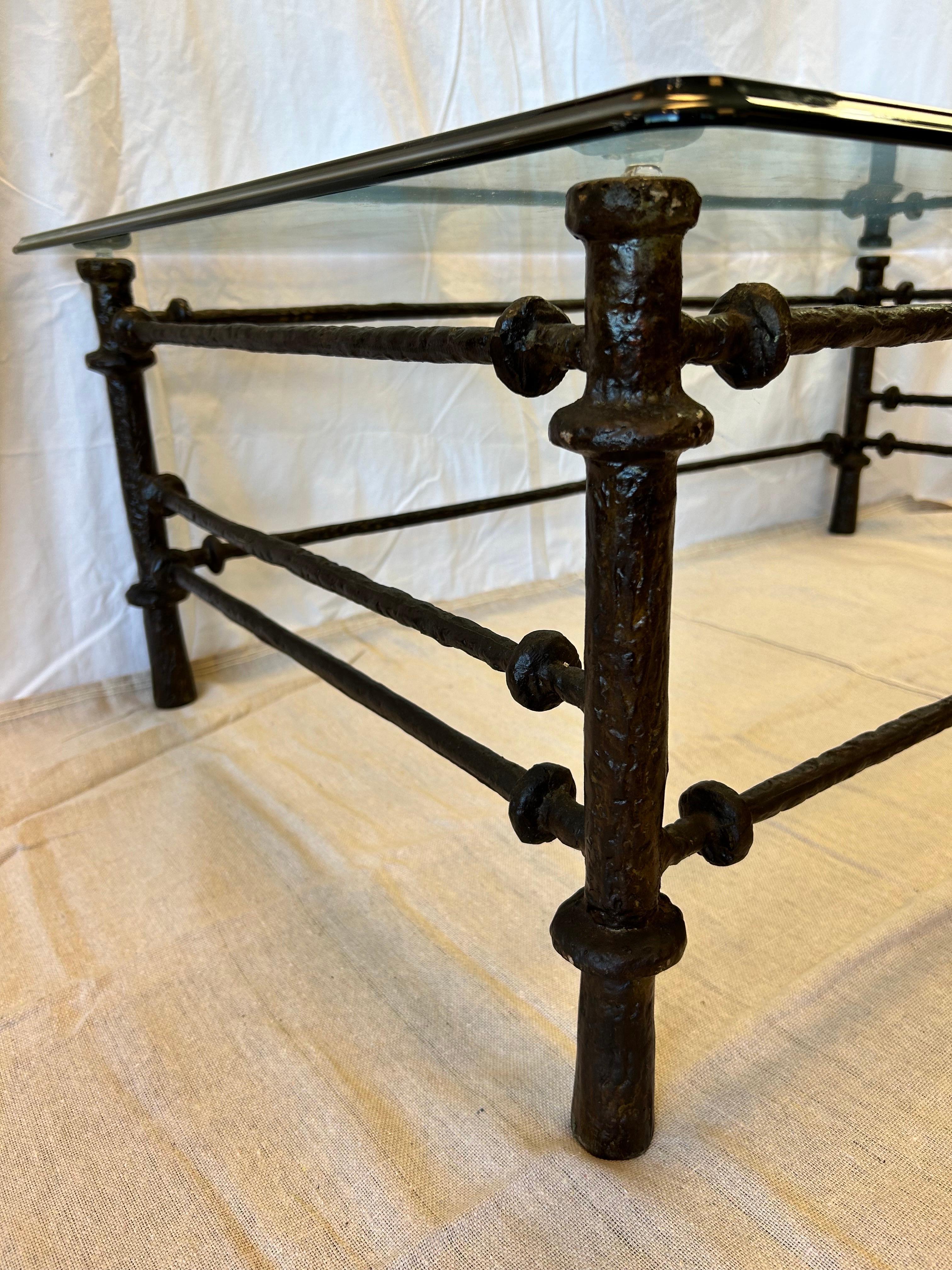 A vintage 1970's era Giacometti inspired Etruscan or Etrusque style coffee or cocktail table with a rounded edge glass top. The table has a cast Brutalist sensibility that Giacometti is known for in his hand hammered bronze originals. This table has