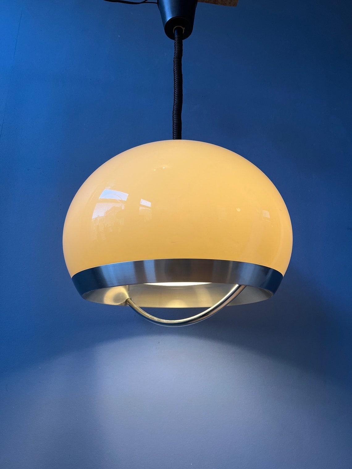 Beautiful space age pendant by Dijkstra in beige/mocca colour and aluminium/metal frame. The shade produces a magnificent glow, reflecting nicely on the chrome arc underneath the shade. The lamps requires an E27 (standard) lightbulb.

Additional