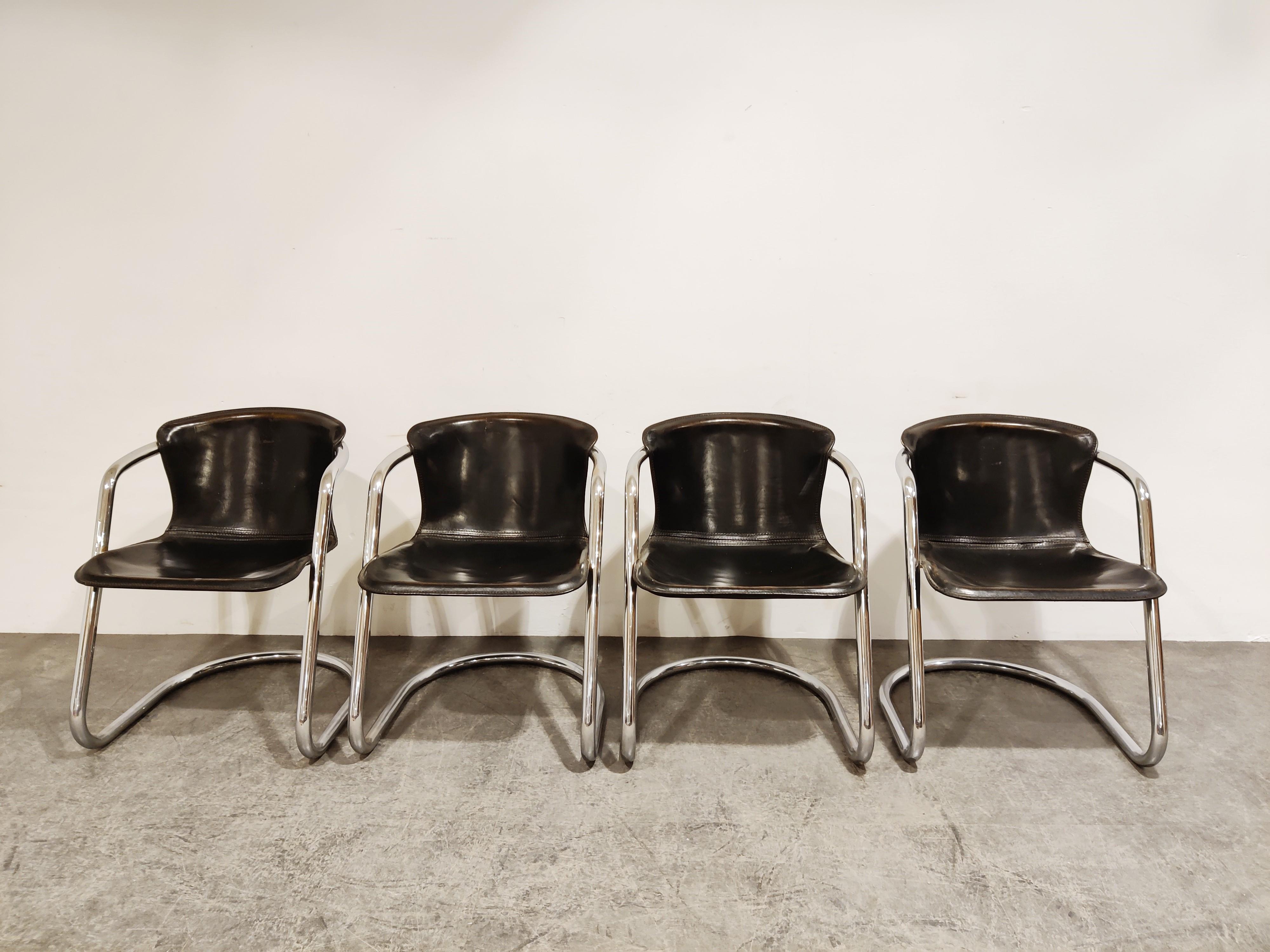 Set of 4 saddle leeather dining chairs designed by Willy Rizzo for Cidue..

The chairs have a beautifully shaped chrome frame and come with the original black leather seats.

Good condition.

This is a rare model.

The chairs still look up