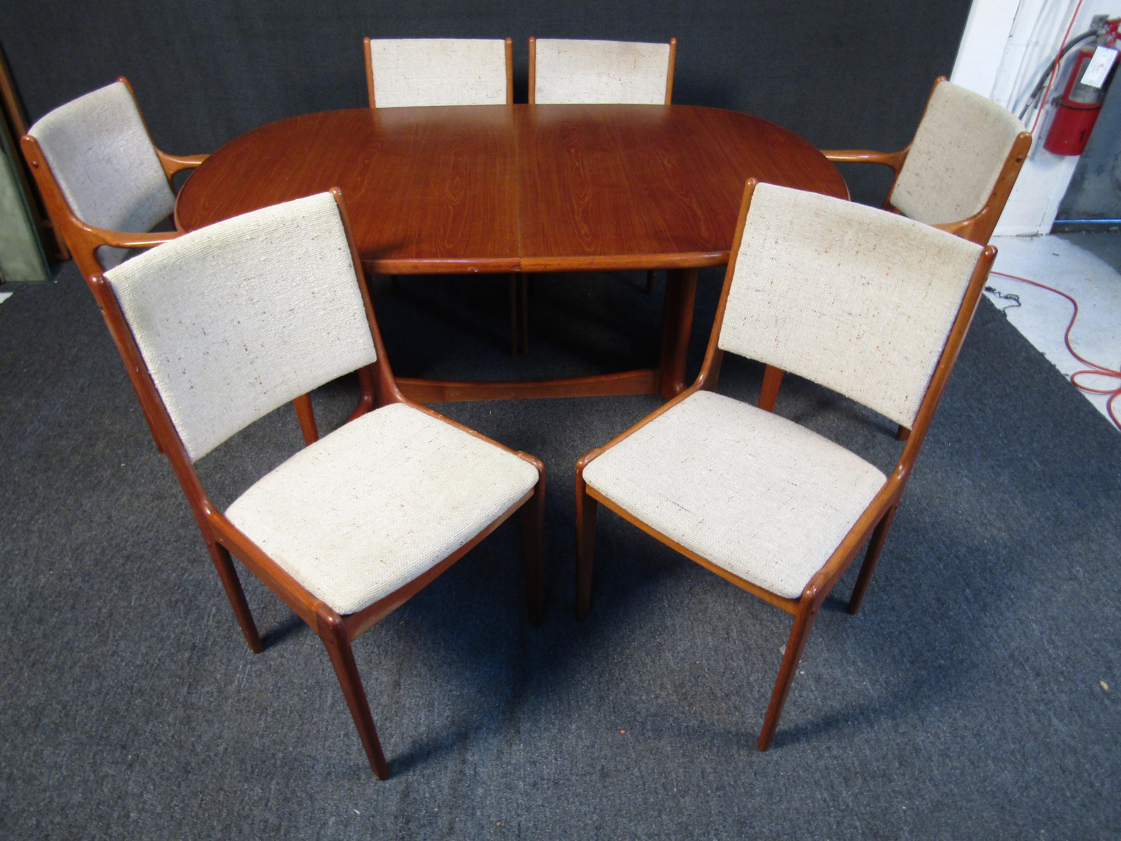 This vintage dining set by Scandinavian Woodworks Co. includes an expanding dining table with a large center leaf, two armchairs, and six dining chairs. The dining table comes with a glass topper to protect the rich teak woodgrain that makes this