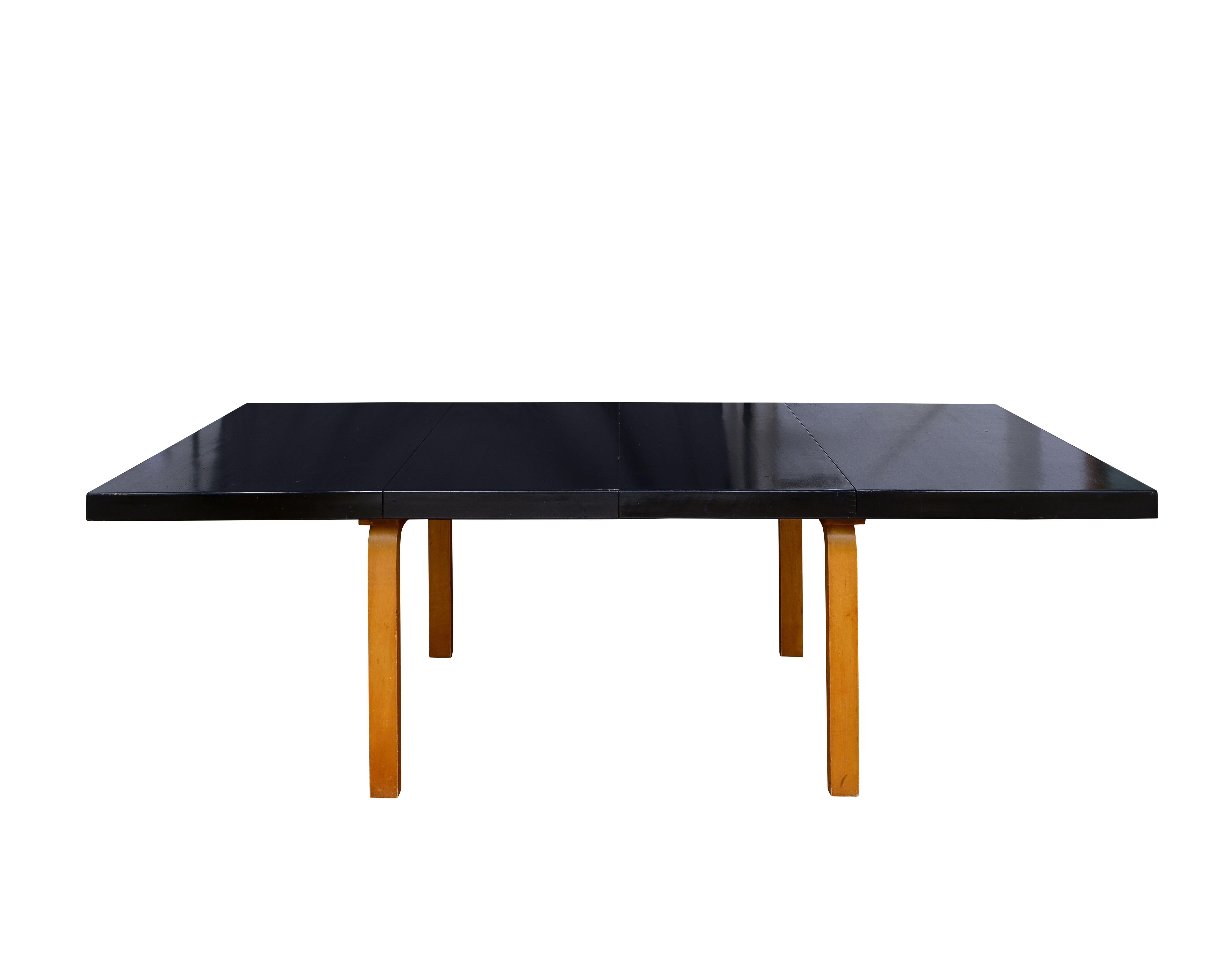 A rare and highly collectible dining set by Alvar Aalto for Artek, dating to the 1930's. The set includes six dining chairs in laminated birchwood sculptural bentwood legs, cut out backrests, and black lacquered seats, paired with a rectangular