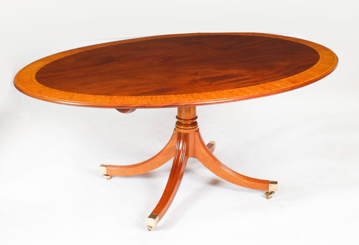 This is a beautiful Regency Revival flame mahogany and satinwood banded oval dining table dating from Circa 1980, made by the Master Cabinet maker William Tillman and bearing his label on the underside, with a matching set of six  Regency Revival