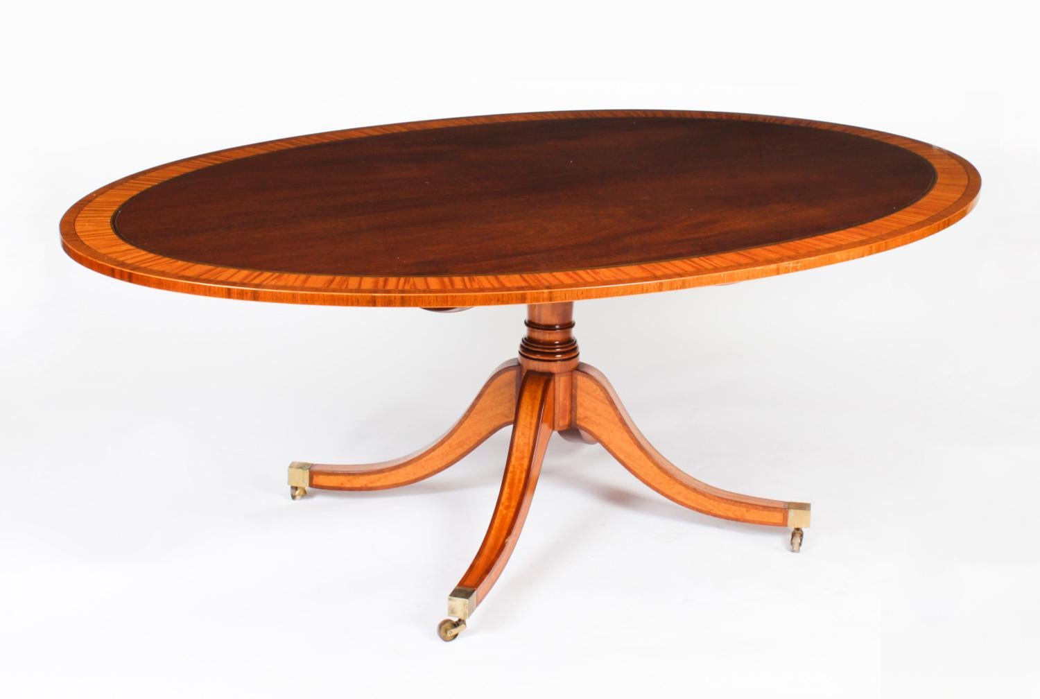 This is a beautiful Regency Revival flame mahogany and Satinwood banded oval dining table dating from Circa 1980, made by the Master Cabinet maker William Tillman and bearing his label on the underside, with a matching set of eight swagback Regency
