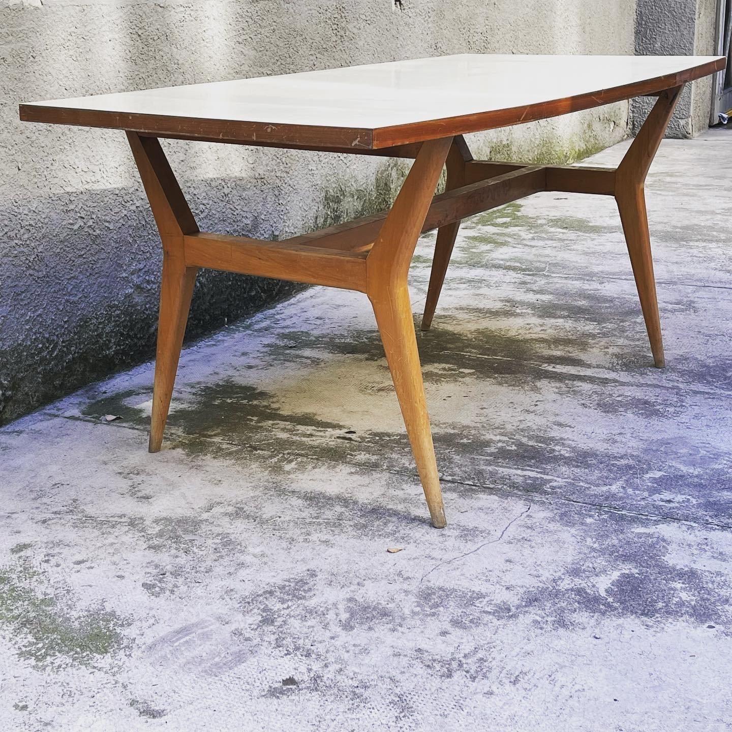 
Beautiful wooden dining table made in Italy in 1950. The wooden dining table has a nice rectangular top, the legs are slightly curved outwards. The top of the dining table is covered with a light laminate in a classic and typical style of the time,