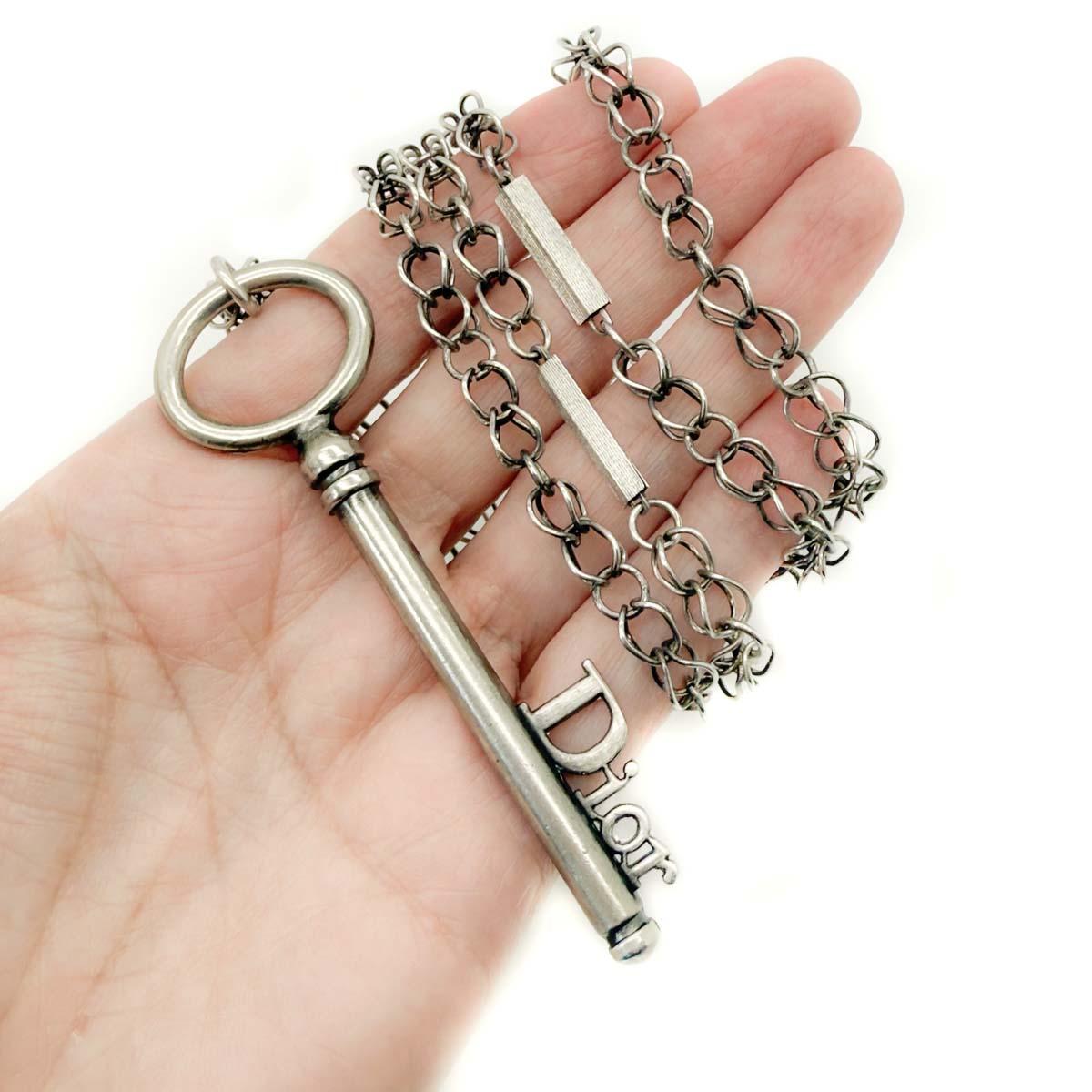 Un collar llave vintage Dior Galliano. Una larga cadena de diseño intrincado con barras gruesas es el preludio perfecto para el gran colgante de llave con logotipo Dior. En metal plateado envejecido, esta pieza patrimonial abre la puerta a los