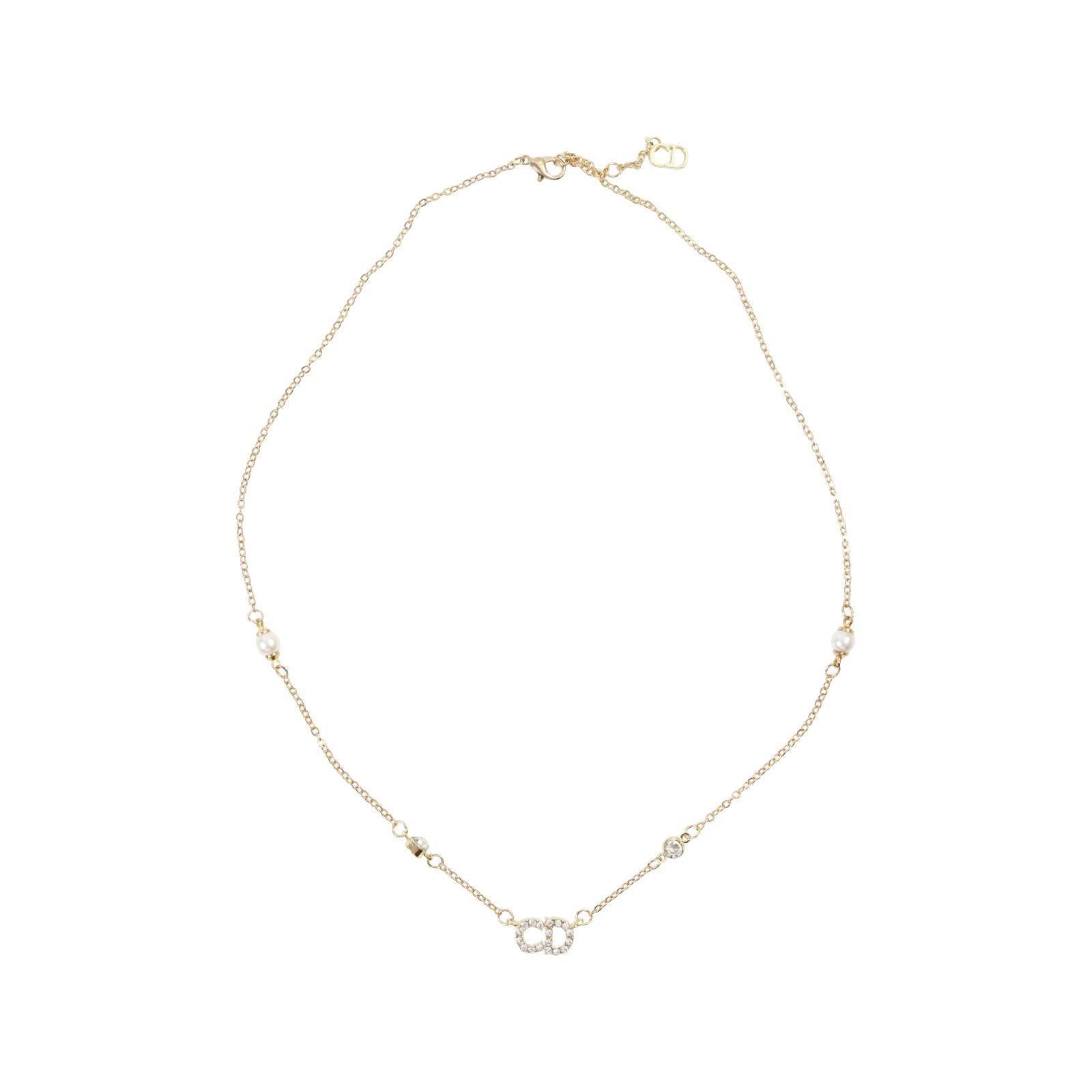 Vintage Dior Gold Tone CD Choker mit Diamanten und Faux Pearl, circa 2000er Jahre. Kleines zierliches Stück mit CD in Diamante mit  dünne Gliederkette und Kunstperle.  Klassisches Stück.

Hat drei Ringe so kann getragen werden 20,5.