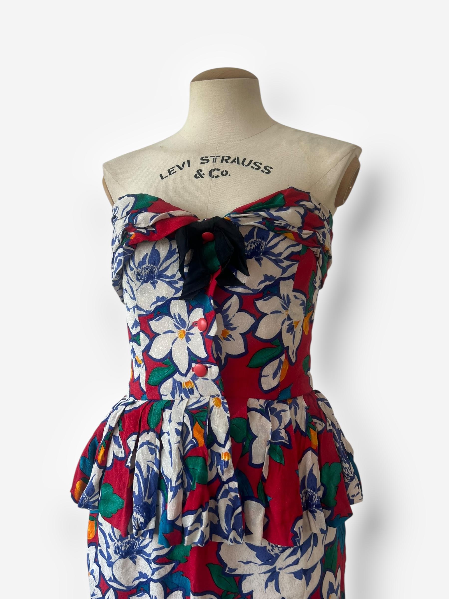

This elegant vintage Dior two-piece set includes a structured silk corset top with button closures and a matching silk skirt featuring a discreet zipper closure. The ensemble showcases a vibrant floral pattern and embodies the timeless