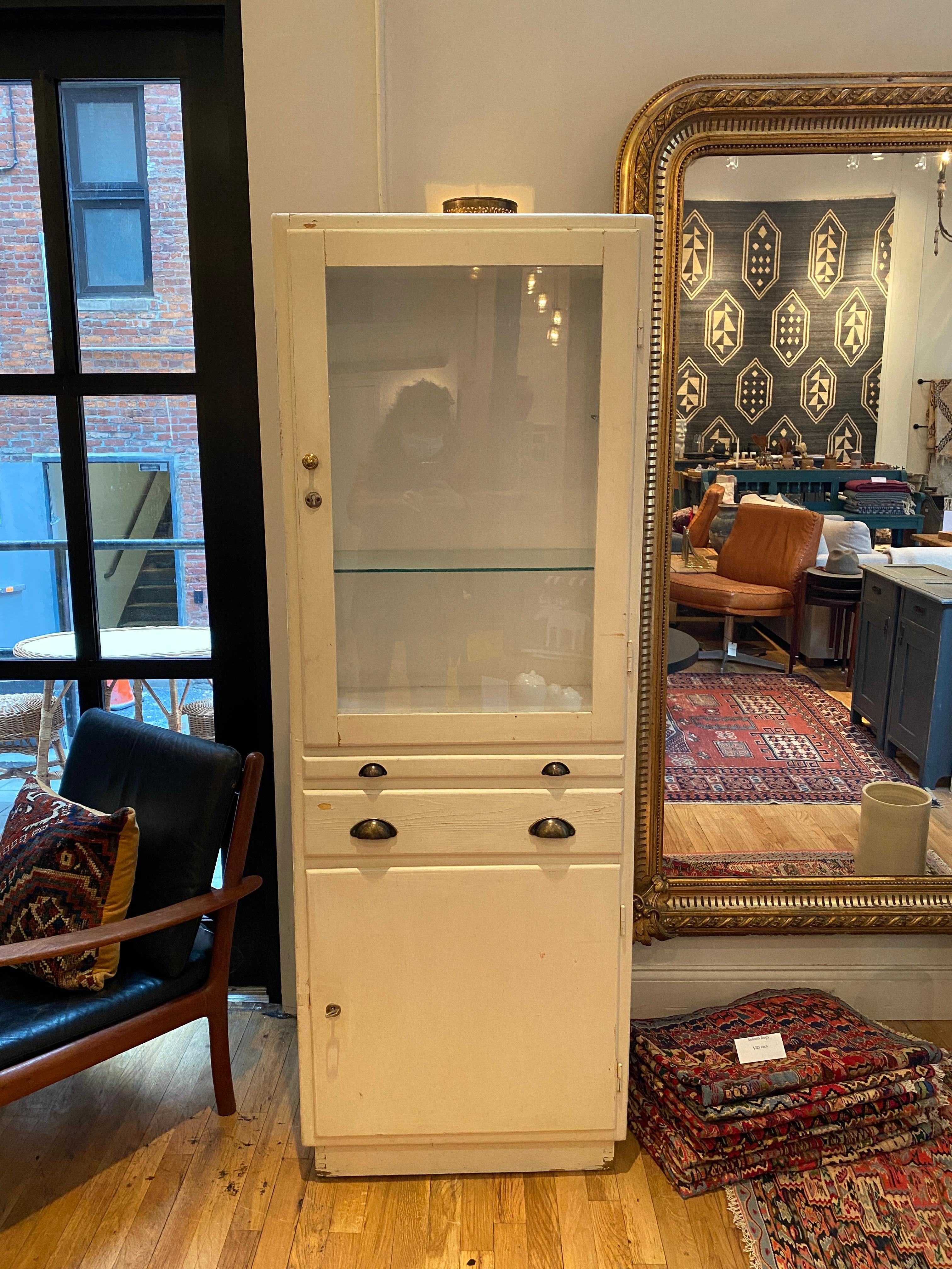French medicine cabinet with glass shelving in the display area, drawer, and cabinet storage. Perfect for displaying anything your heart desires ranging from antique china to decorative pieces. Endless versatility, can be used in any area of the