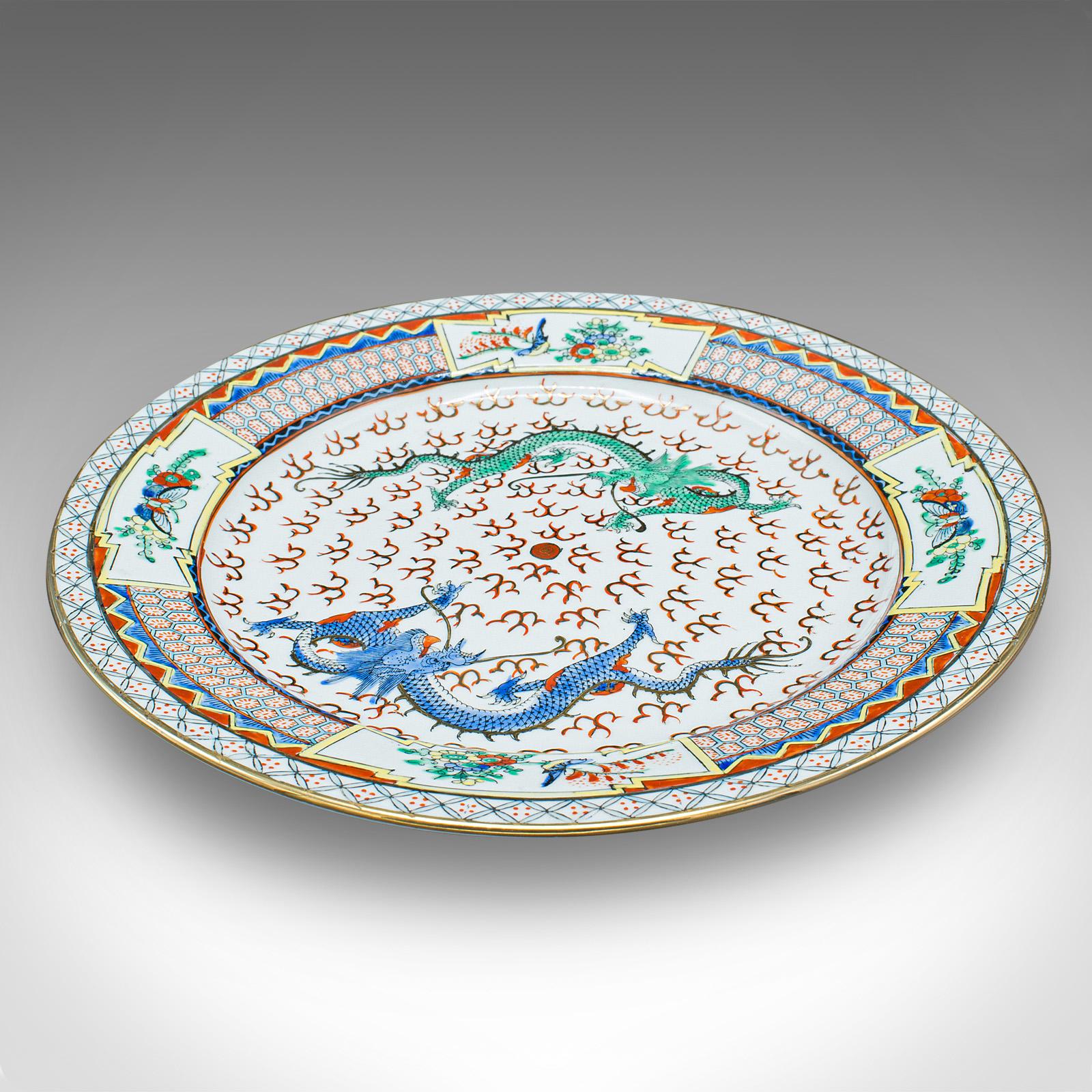 This is a vintage display plate. A Chinese, ceramic serving dish in Art Deco taste, dating to the early 20th century, circa 1930.

Profusely decorated with dragons and fine pattern detail.
Displays a desirable aged patina and in good