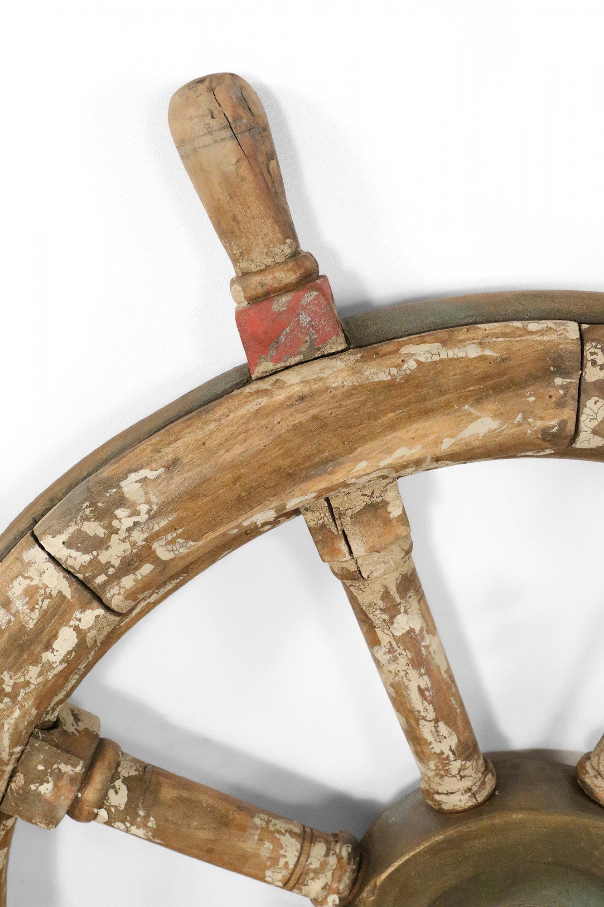 Vintage ship's wheel with distressed brown and beige finish with red painted accents and heavy patinated bronze center.