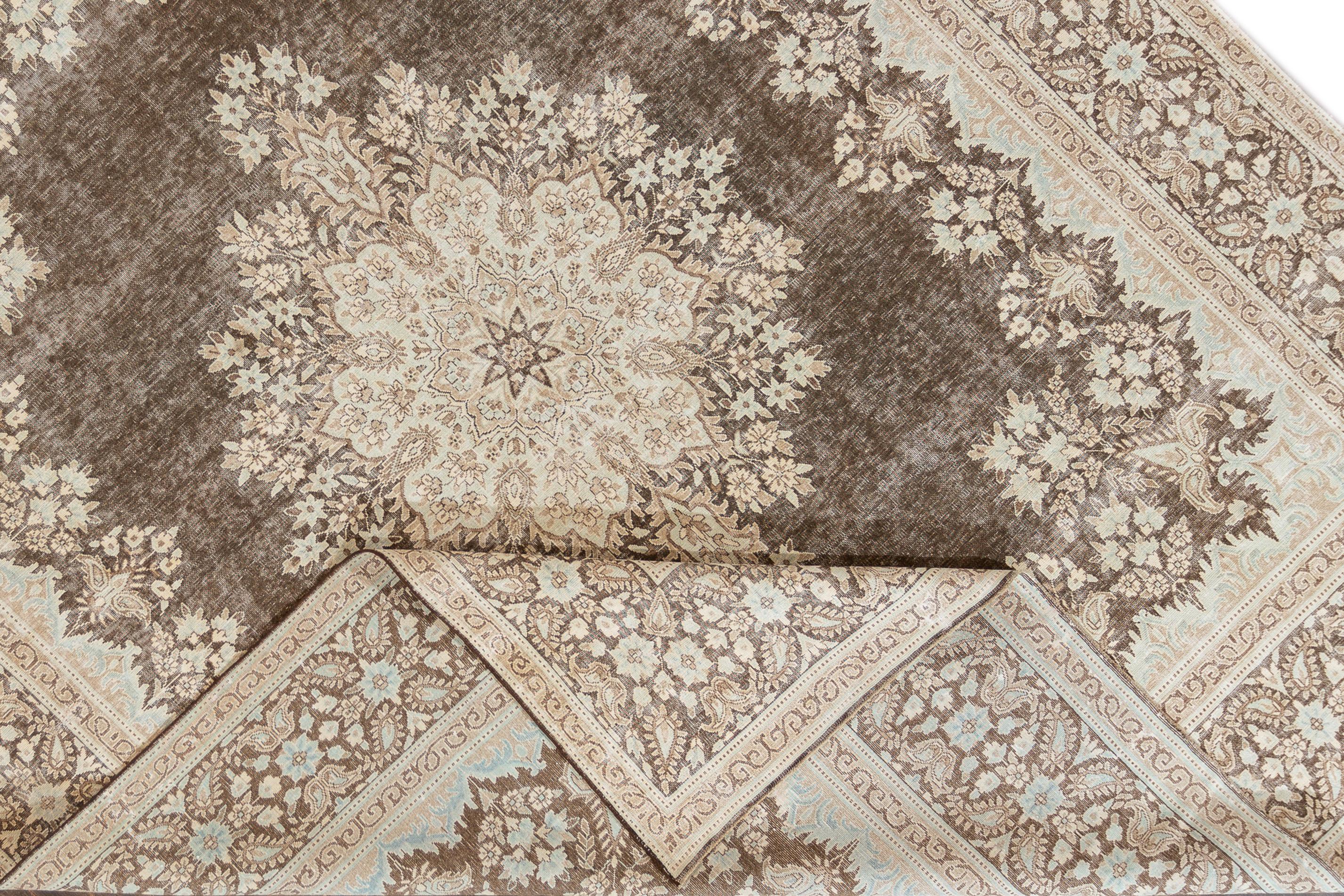 Vintage distressed rug with a brown field and pale blue and tan accents in a floral medallion design. This hand knotted wool rug measures 9'9
