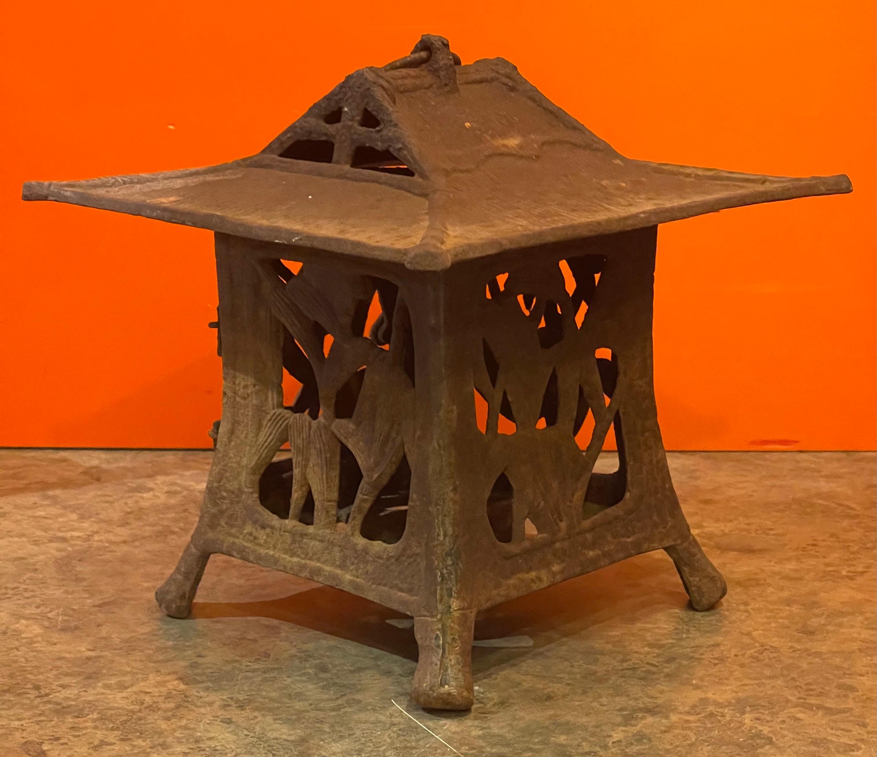Vintage distressed cast iron Japanese pagoda lantern, circa 1950s. The lantern has a great distressed rust patina and a wonderful look. The piece is solid and functional and has a small door that opens to allow a candle to be inserted. The pagoda