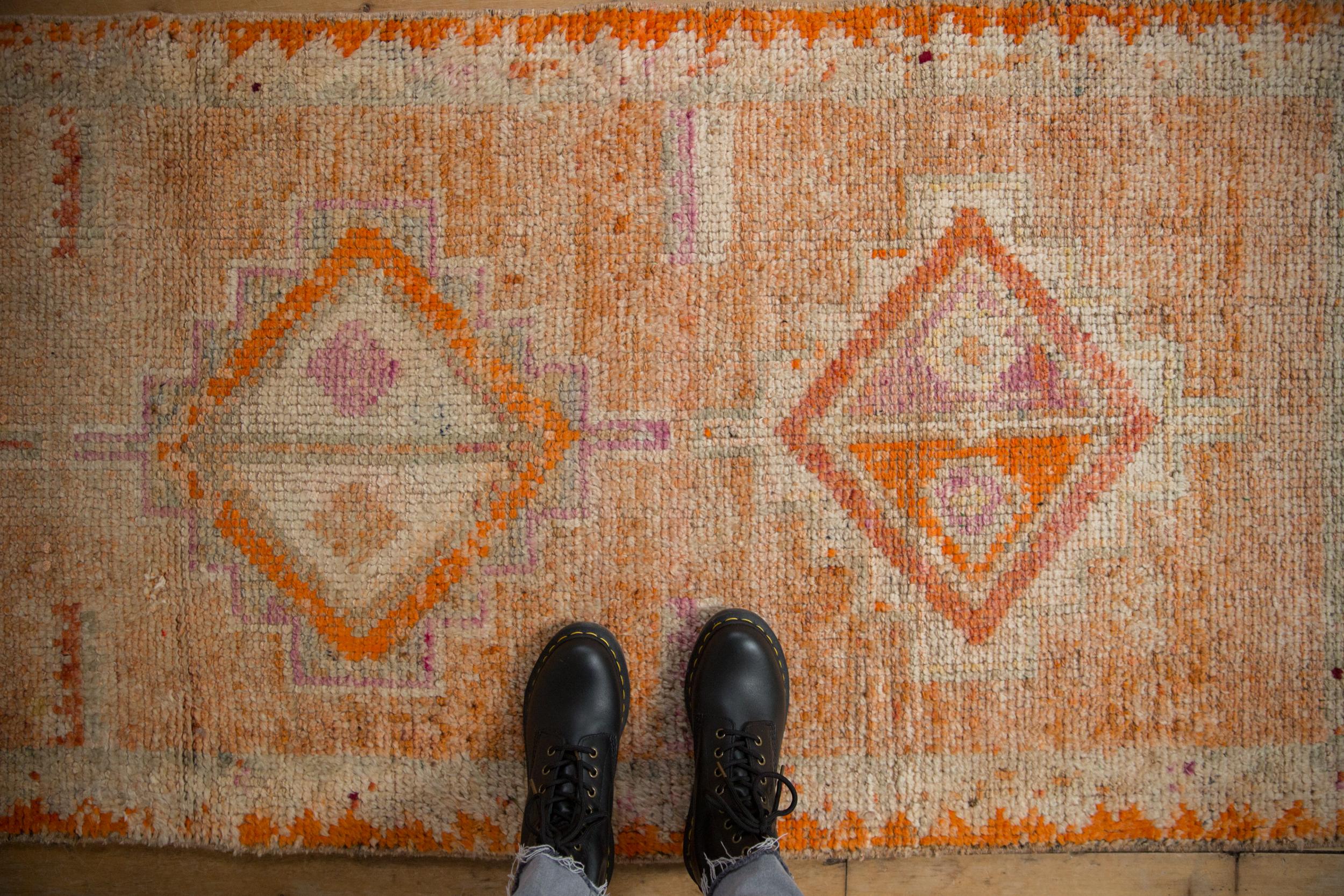 :: Single column center medallion in diamond shaped contour and interior pinwheel design elements atop an abrashed ground with zig zag narrow banded main border. Colors and shades include: Pale tangerine orange, bright tangerine orange, dusty