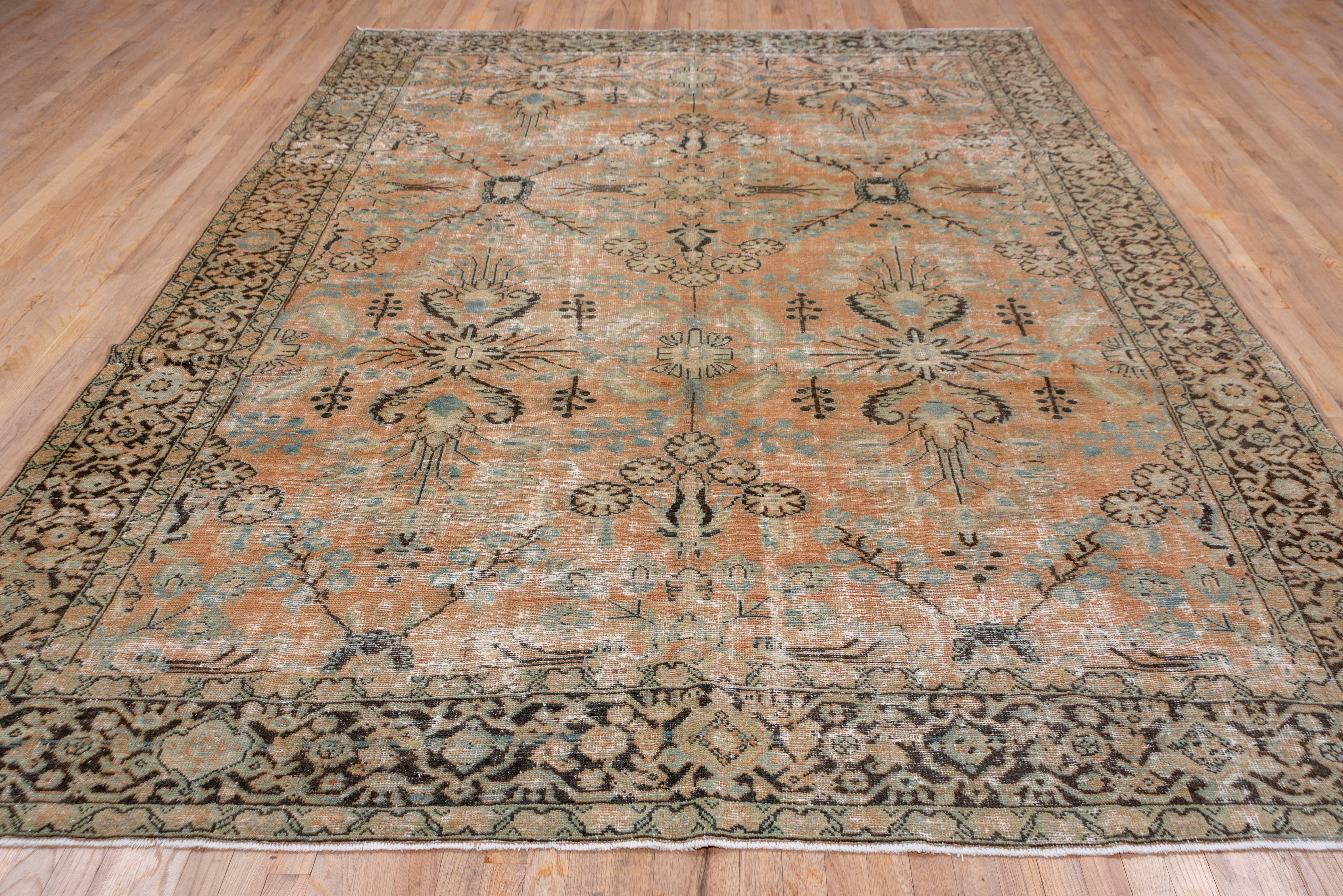 This predominantly light colored west Persian village carpet has a burnt pale apricot field with a spacious, large pattern design of rosettes, floral sprays and small complete flowers. There are a few teal accents. The brick main border displays