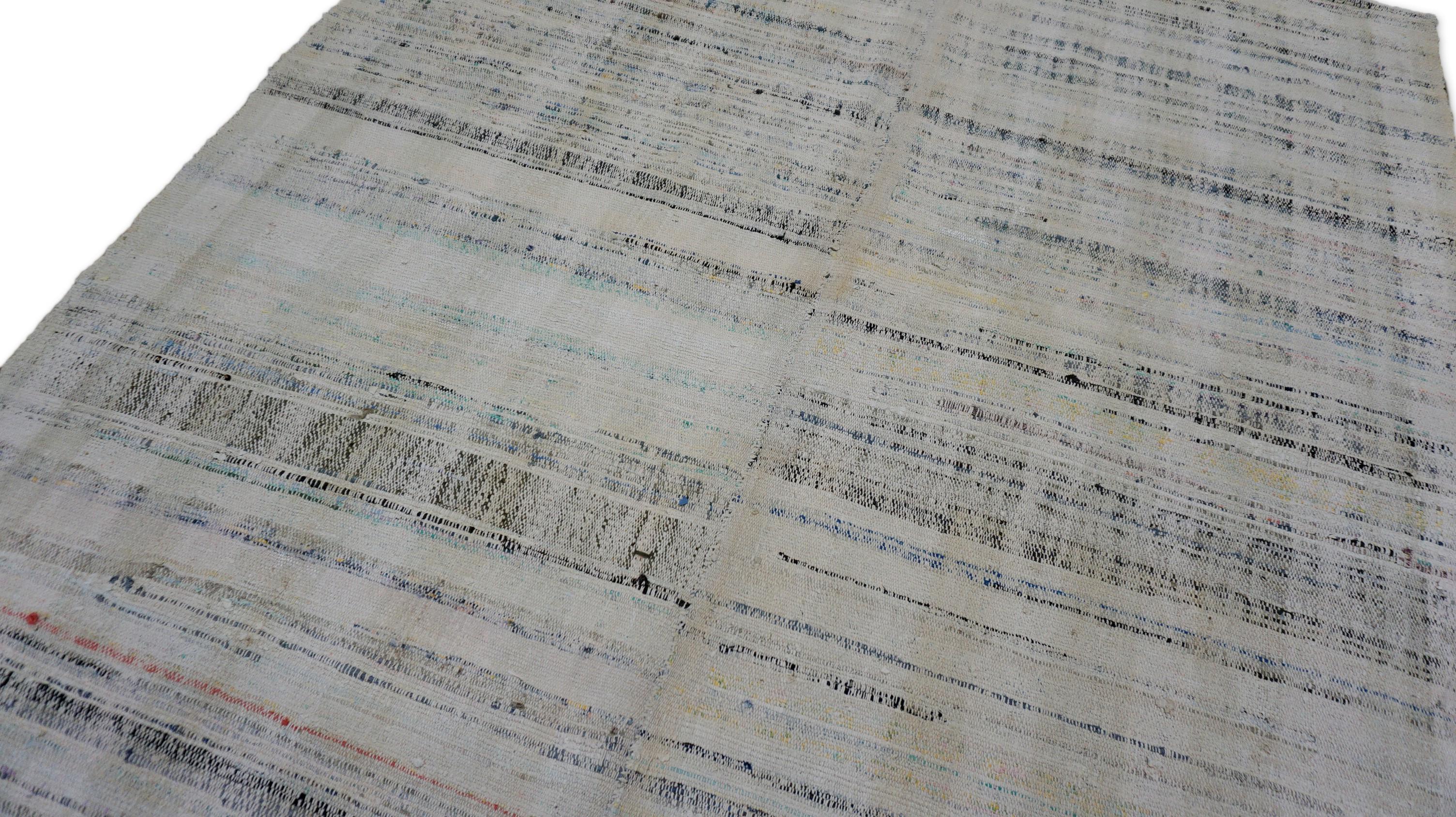 Dieser handgewebte Wollkelim ist ein subtiles Meisterwerk von ruhiger Eleganz, das sich durch eine sanfte Mischung aus verblichenen Grau-, Hellbraun- und weichen Anthrazittönen auszeichnet, die in dezenten horizontalen Streifen angeordnet sind. Der