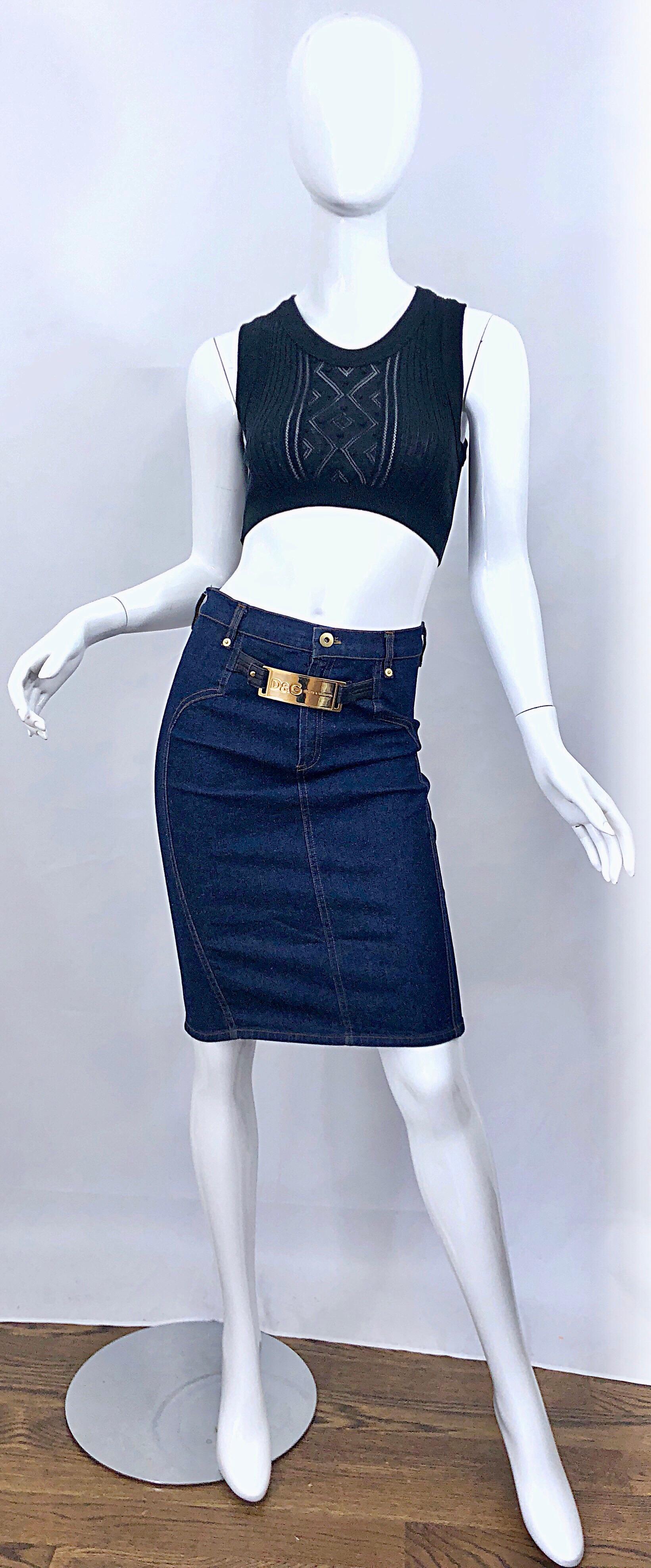 Iconic and sexy late 90s / early 2000s DOLCE & GABBANA blue jean denim high waisted bodycon pencil skirt. Features a gold logo embossed buckle attached to black leather straps. Button at center waistband, with metal zipper fly. 96% Cotton 4%