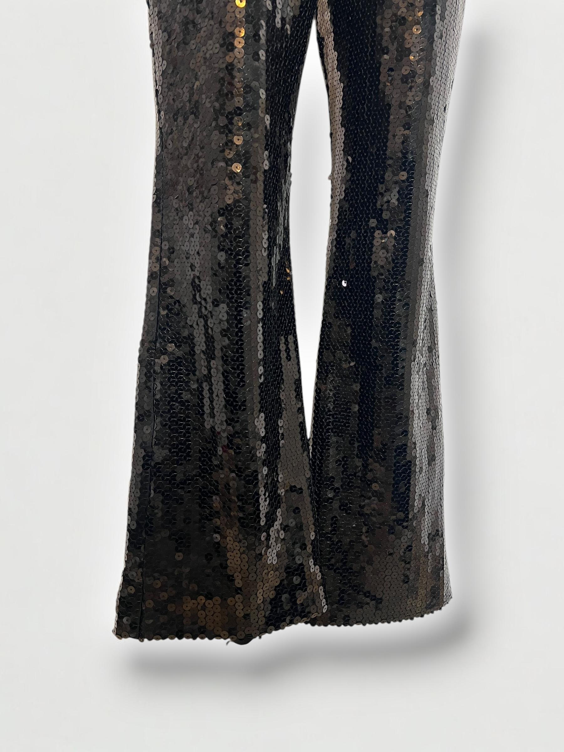 Retrouvez le glamour de la fin des années 1990 avec ce pantalon à paillettes éblouissant de Dolce & Gabbana, datant d'environ 1999. Dotées d'une silhouette légèrement évasée et d'une finition noire brillante, elles incarnent l'esthétique audacieuse