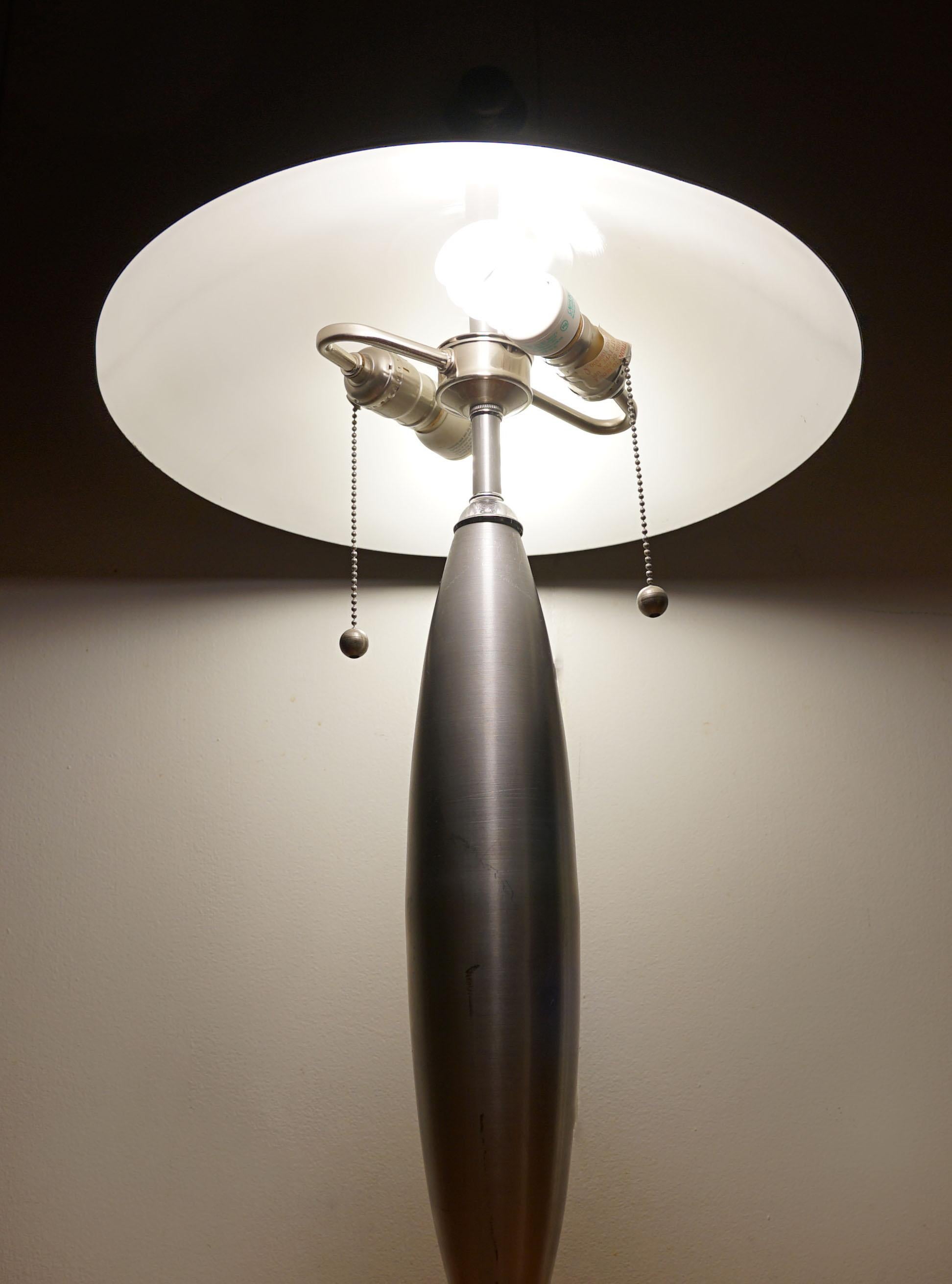 This lamp is special, and it is has a sleek futuristic look and brushed steel or chrome exterior. The lamp silhouette is striking with the wide dome and spherical stand. The double chains control dual sockets which allow for focused lighting. 
This