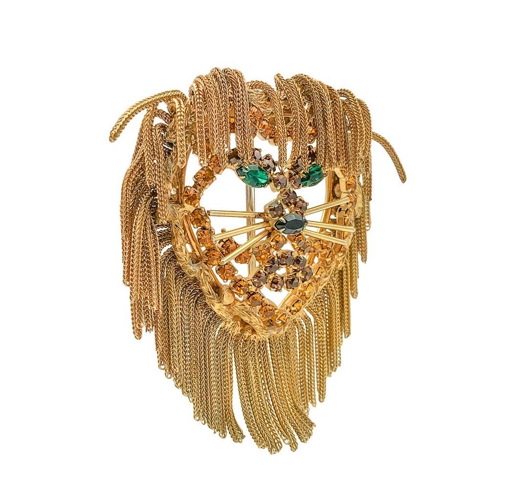 A Vintage Dominique Lion Brooch. Crafted in gold plated metal and crystals. An impressive lion figural brooch with a fabulous tassel mane. The face depicted in crystals of citrine and emerald colours. In very good overall vintage condition - most