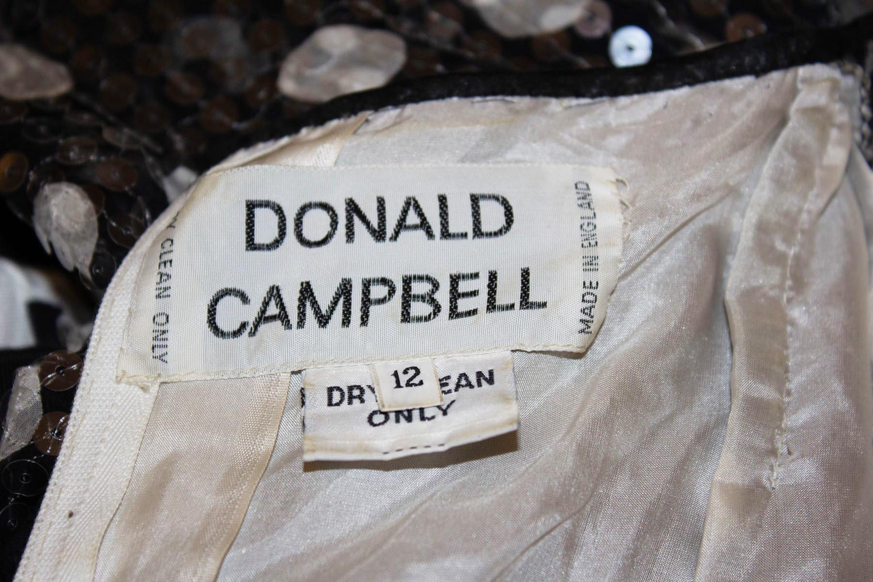 Une amusante robe de soirée vintage de Donald Campbell.
La robe est une merveilleuse combinaison, la partie supérieure est ornée de paillettes subtiles.  la décoration et les manches complètes, la surface de la jupe est en  une superbe impression en