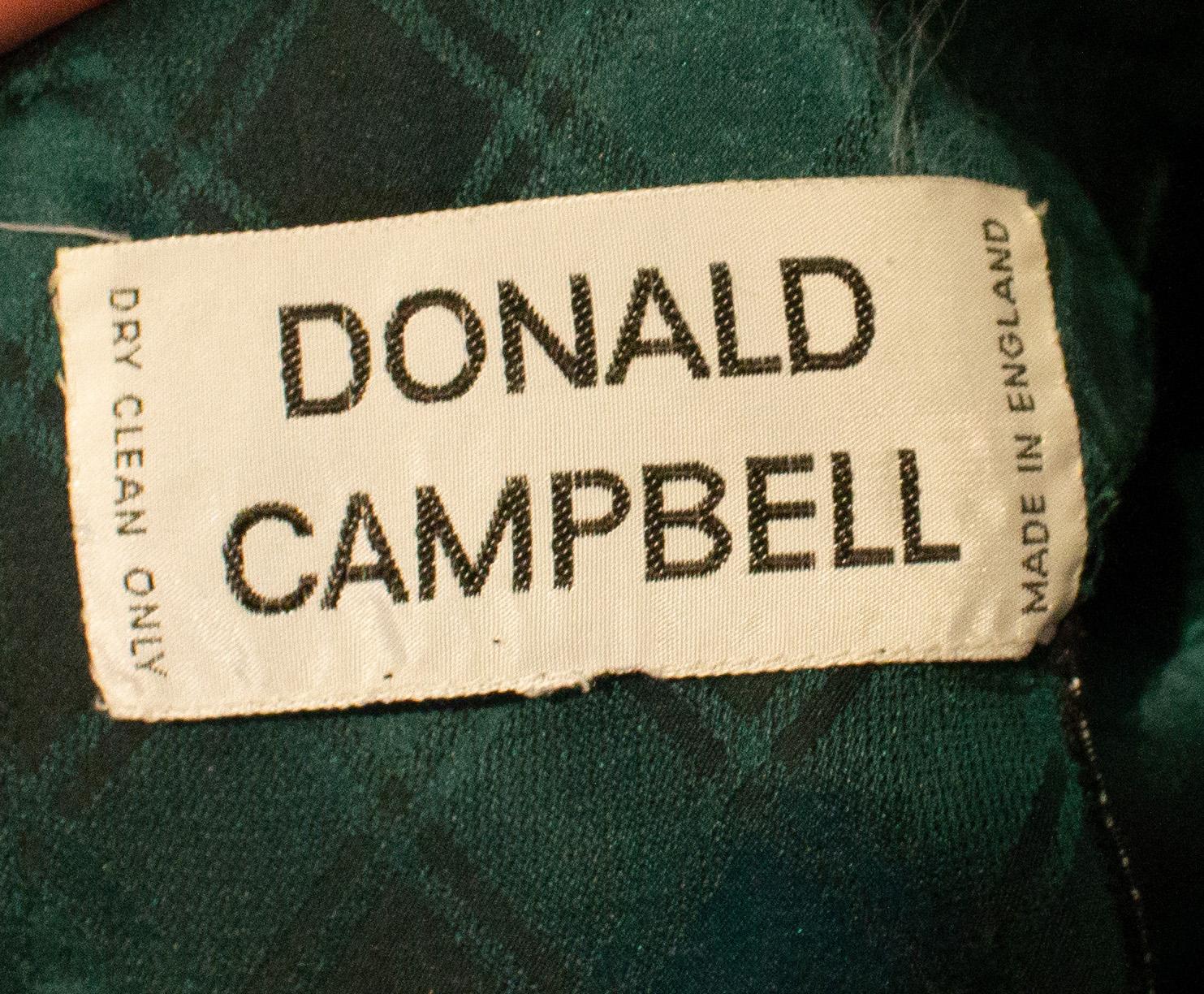 Une robe de soirée chic en soie de Donald Campbell.  La robe a un décolleté en V  avec des plis sous la poitrine. Il est doté d'une ouverture à boutons en tissu dans le dos, d'une ouverture zippée cachée dans le bas du dos et d'une fermeture à