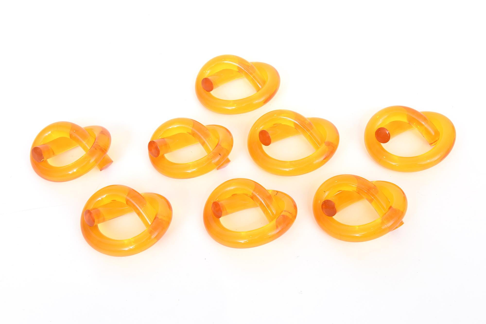 These iconic vintage set of 8 lucite Dorothy Thorpe twisted napkin rings are of the amber and Hermes orange color palette and the rarest ones and hardest color to find. They are called the pretzel design. They are rendered in bent tubular shape of