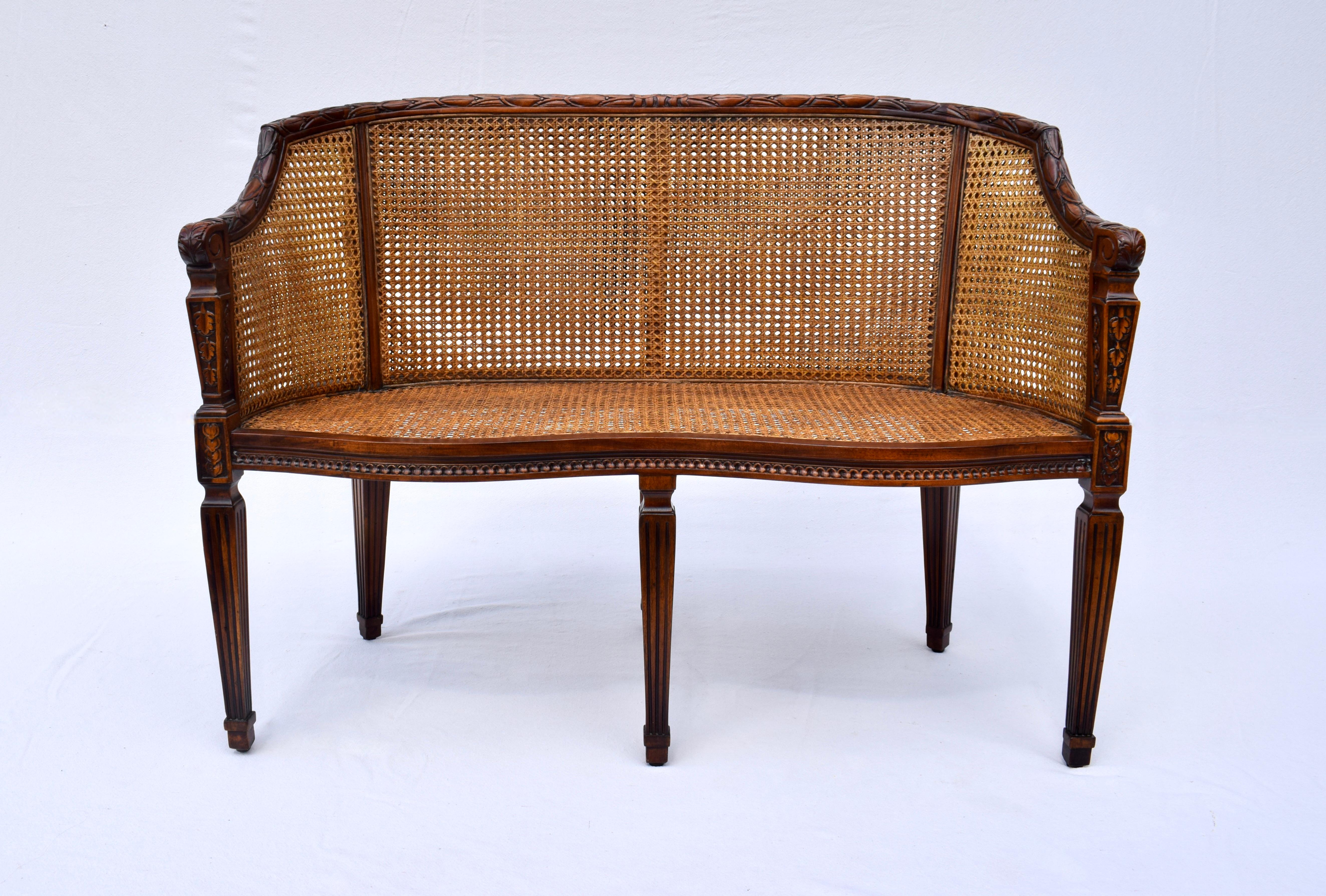 Vintage double caned settee or bench with French faux Bois carvings throughout the frame. Features carved serpentine front & tapered reeded legs with plush down filled custom cushion in embroidered Satin. Seat: 17.5.
