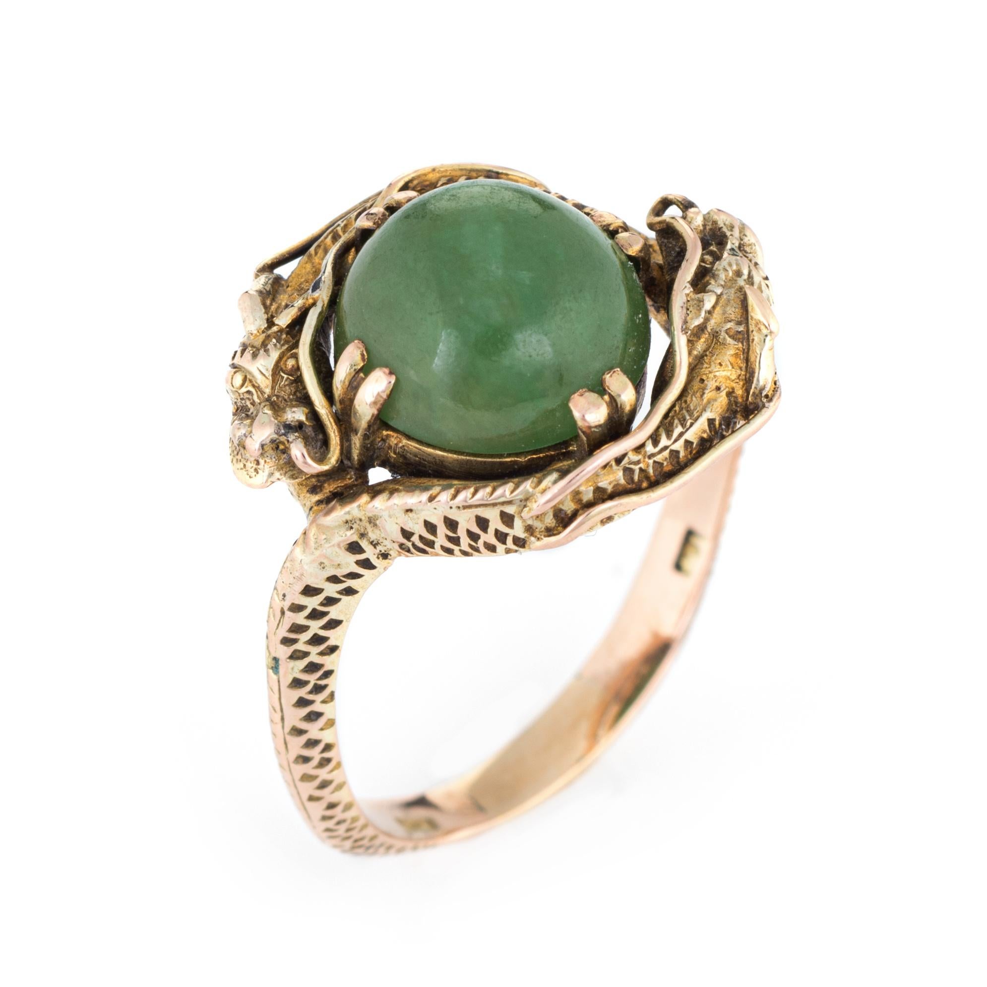 Finely detailed vintage double dragon ring (circa 1960s to 1970s), crafted in 14 karat yellow gold. 

Green jade is cabochon cut and measures 9mm (estimated at 3.25 carats). The jade is in excellent condition and free of cracks or chips. 

The ring