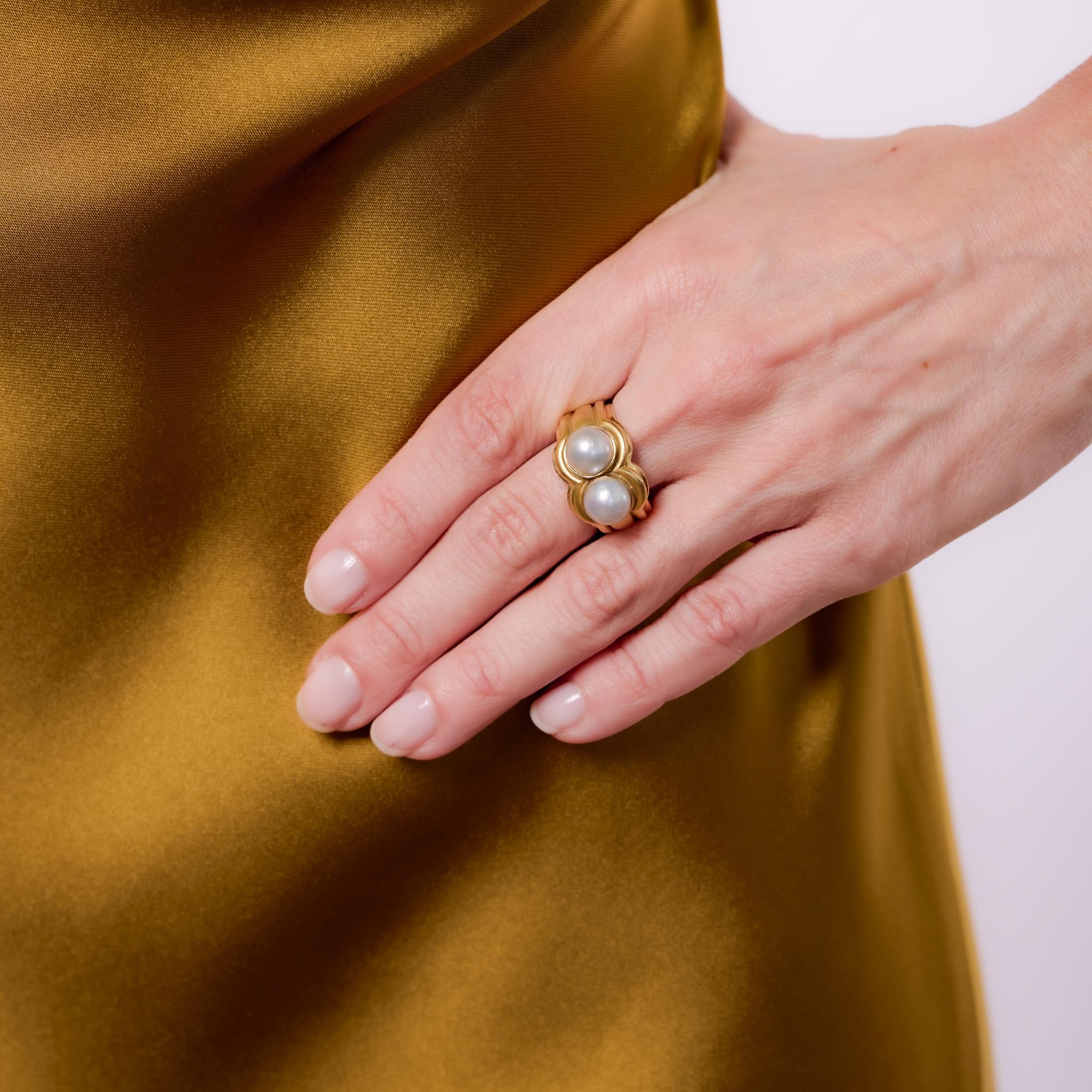 Fabriquée dans les années 1980, cette bague vintage à double perle présente deux perles assorties, chacune mesurant environ 8,08 mm, serties dans un design en or jaune 18 carats. La forme audacieuse et très polie de la bague met en valeur l'éclat