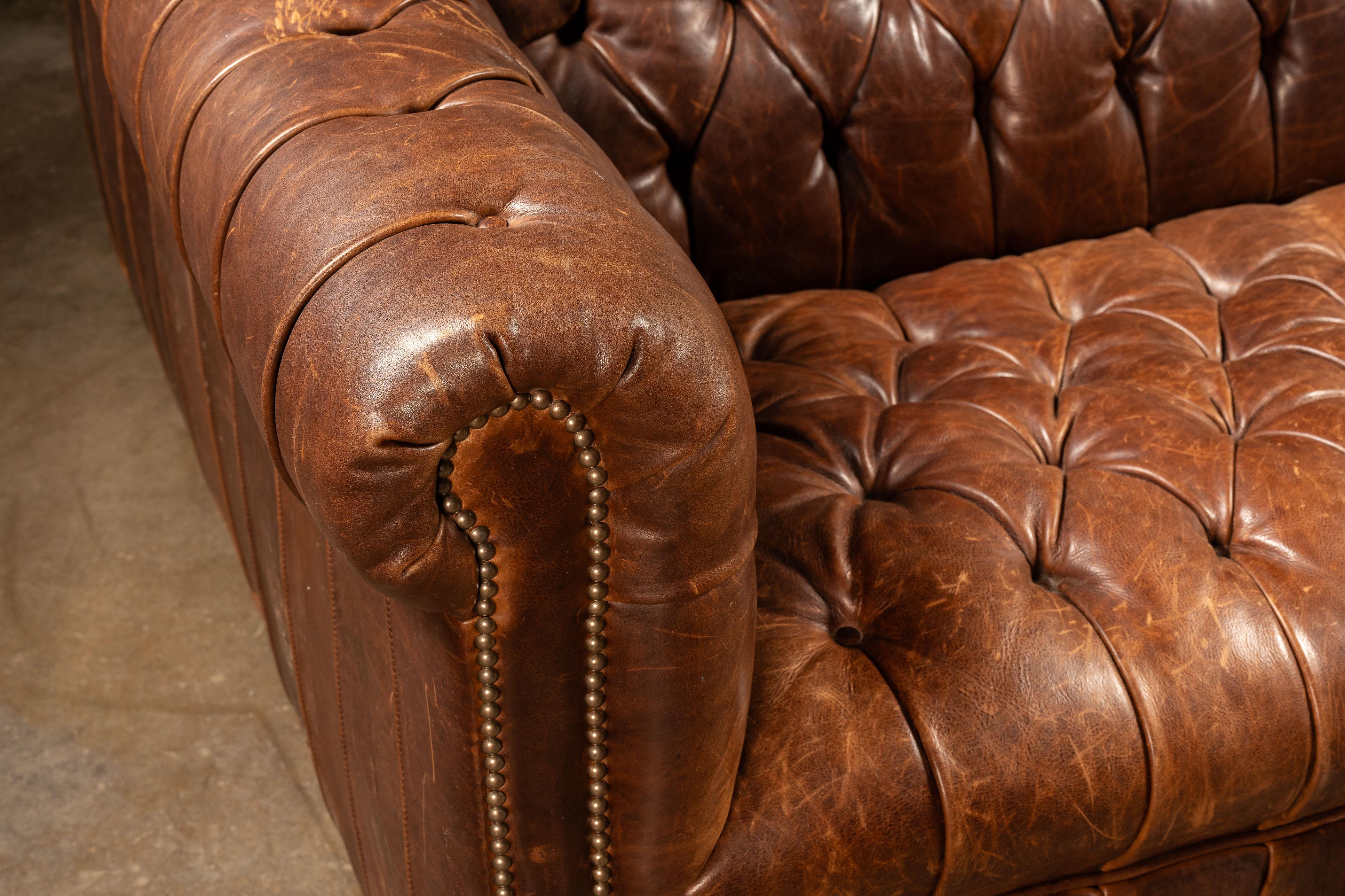 Un canapé Chesterfield vintage, non marqué, avec une assise double et un support suffisant pour plusieurs personnes.

Cette pièce est fabriquée en cuir pleine fleur et présente une riche nuance de marron. Les dossiers et les assises étroitement
